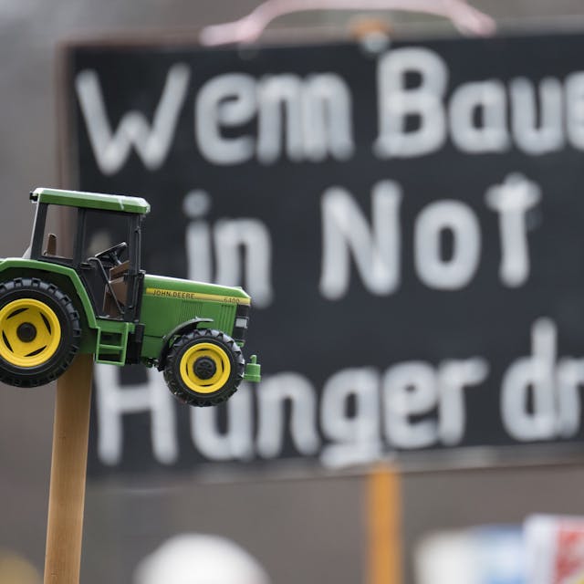„Wenn Bauer in Not Hunger droht“ steht während einer Demonstration in Berlin auf einem Plakat, davor ist ein Spielzeugtraktor zu sehen.