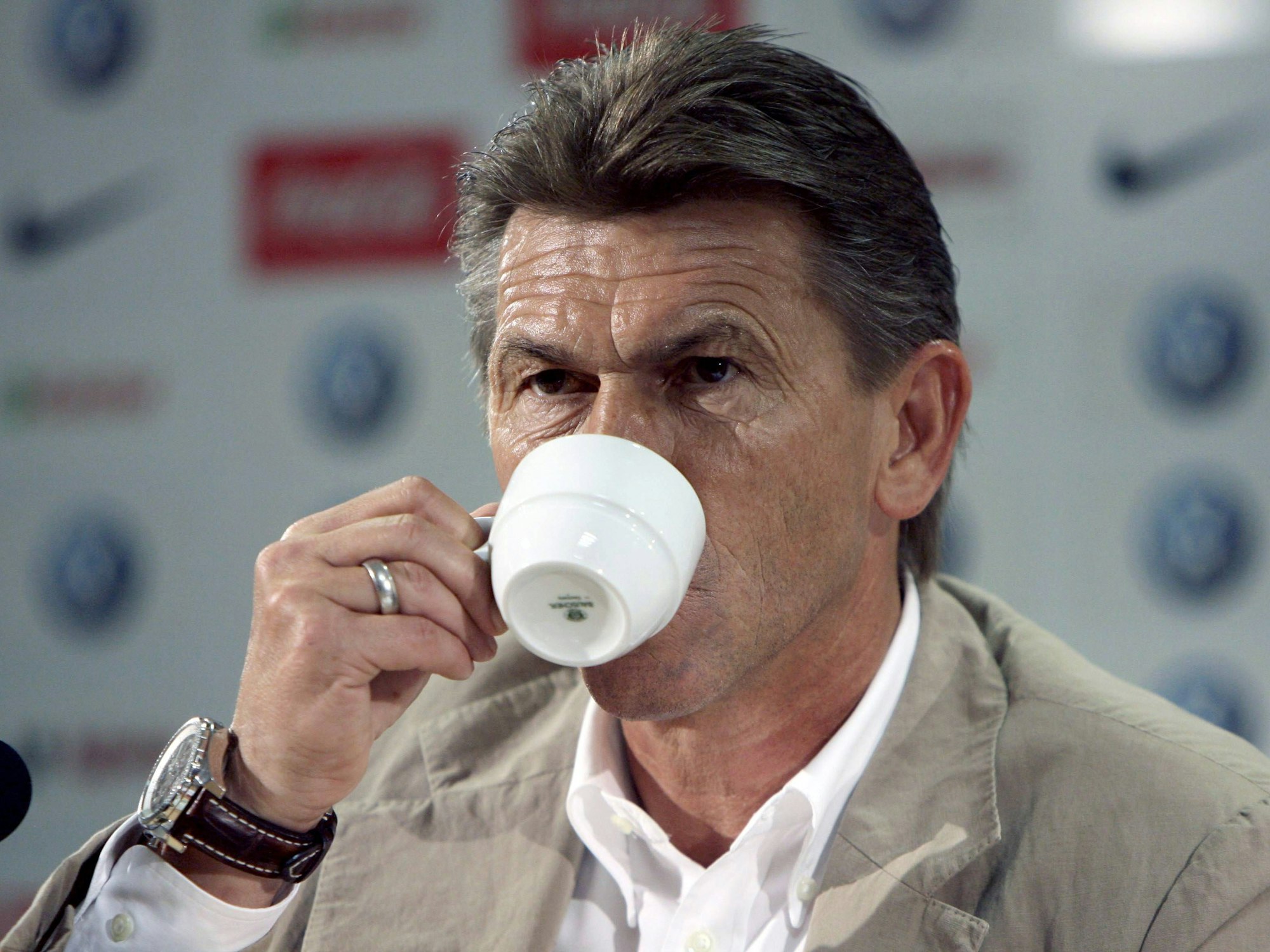 Klaus Augenthaler trinkt bei einer Pressekonferenz Kaffee.
