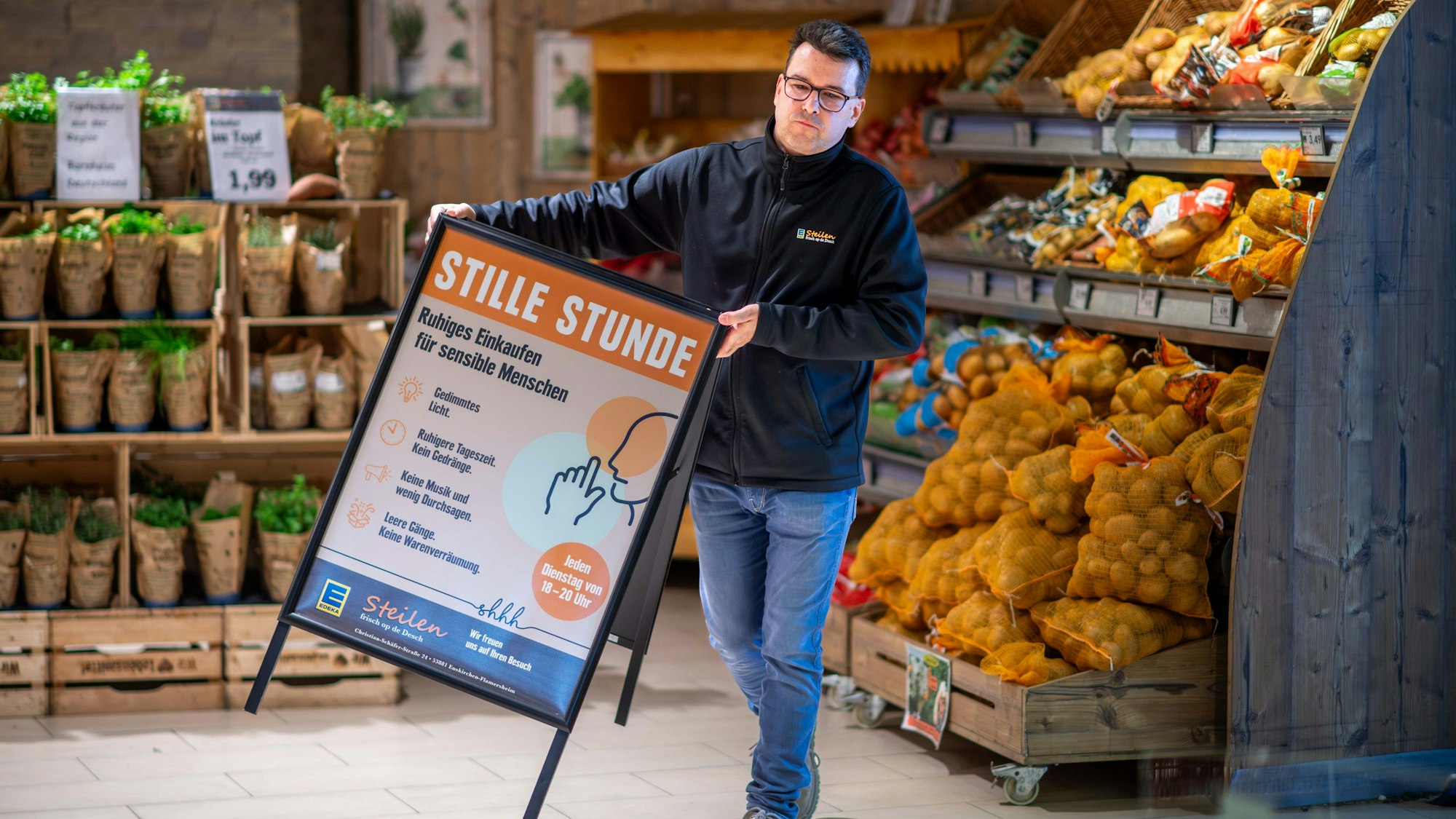 Dirk Steilen trägt in seinem Edeka-Markt einen Aufsteller, der auf die Stille Stunde hinweist, in der auf grelles Licht und Werbung verzichtet wird.