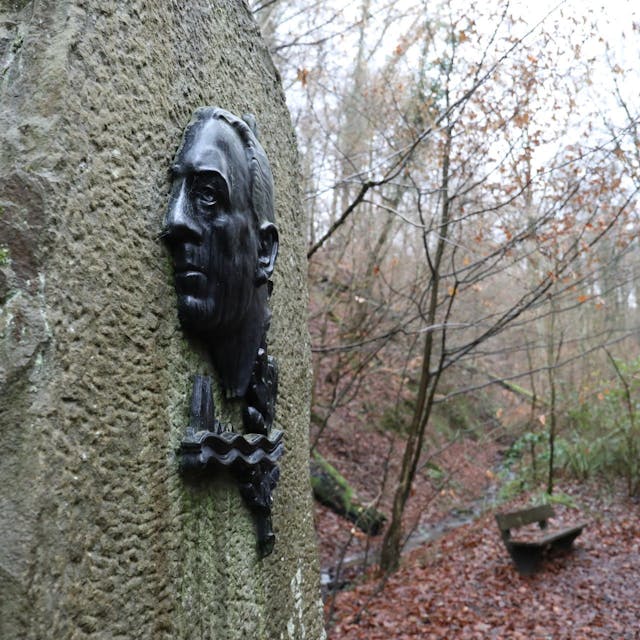 An einem großen Stein ist Bronzerelief mit einem Porträt von Willi Ostermann angebracht.&nbsp;