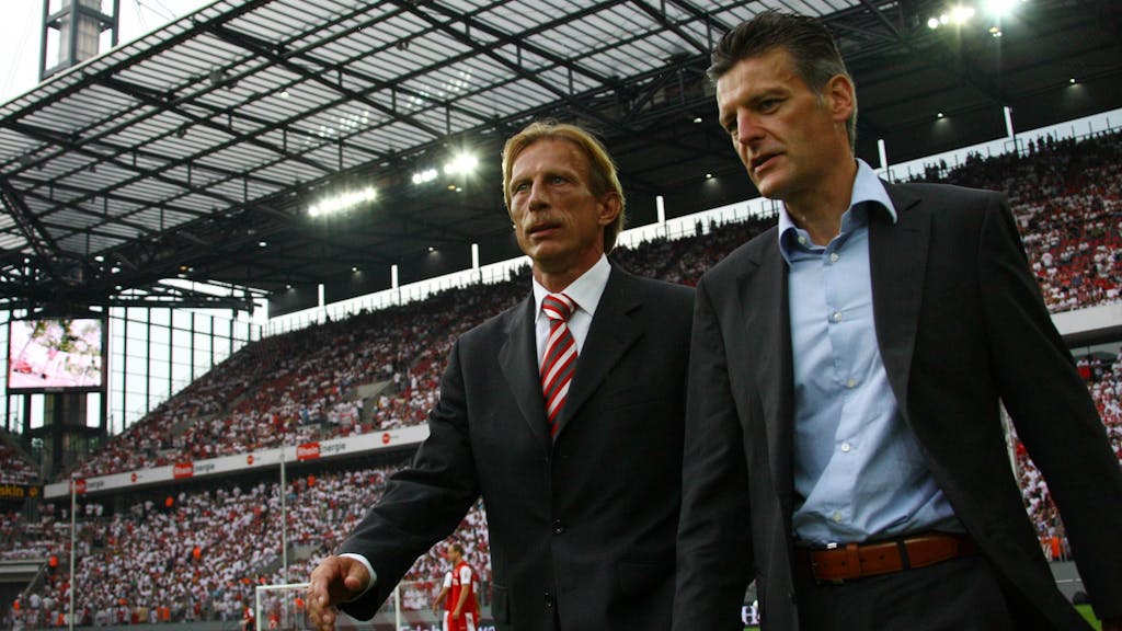 Trainer Christoph Daum (li.) und Pressesprecher Christopher Lymberopoulos betreten gemeinsam den Rasen im Kölner Rhein-Energie-Stadion.