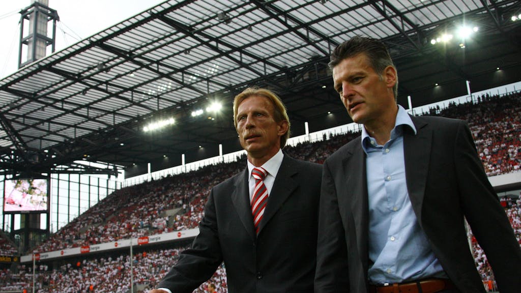 Trainer Christoph Daum (li.) und Pressesprecher Christopher Lymberopoulos betreten gemeinsam den Rasen im Kölner Rhein-Energie-Stadion.