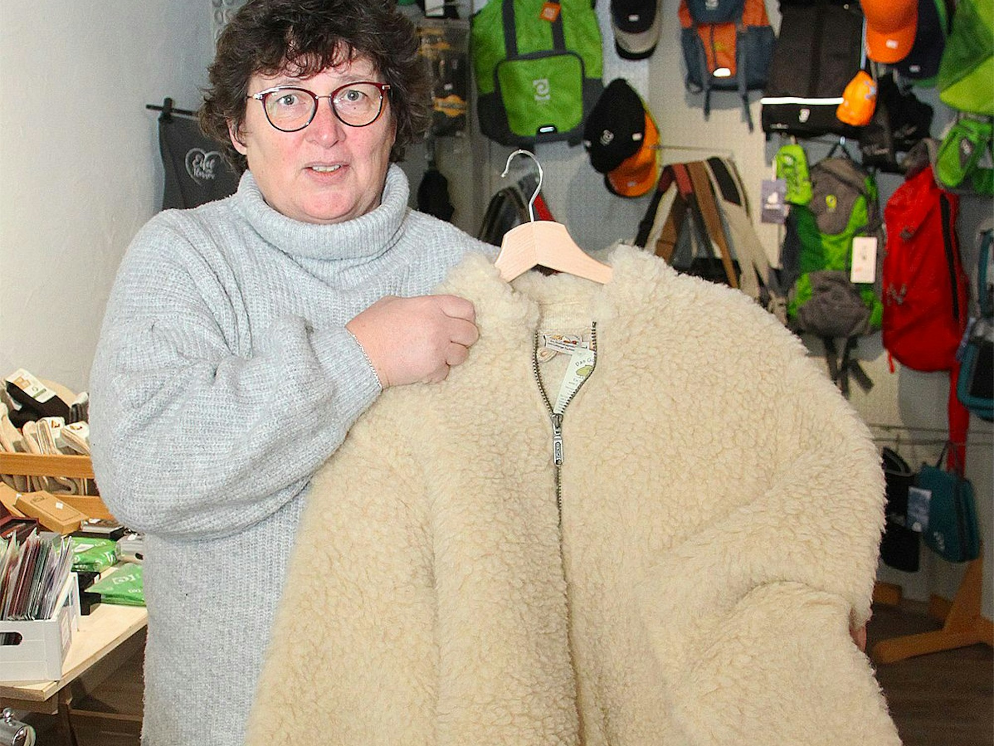 Monika Caspers hält eine Jacke aus Schafswolle in der Hand, die in ihrem Hofladen angeboten wird.