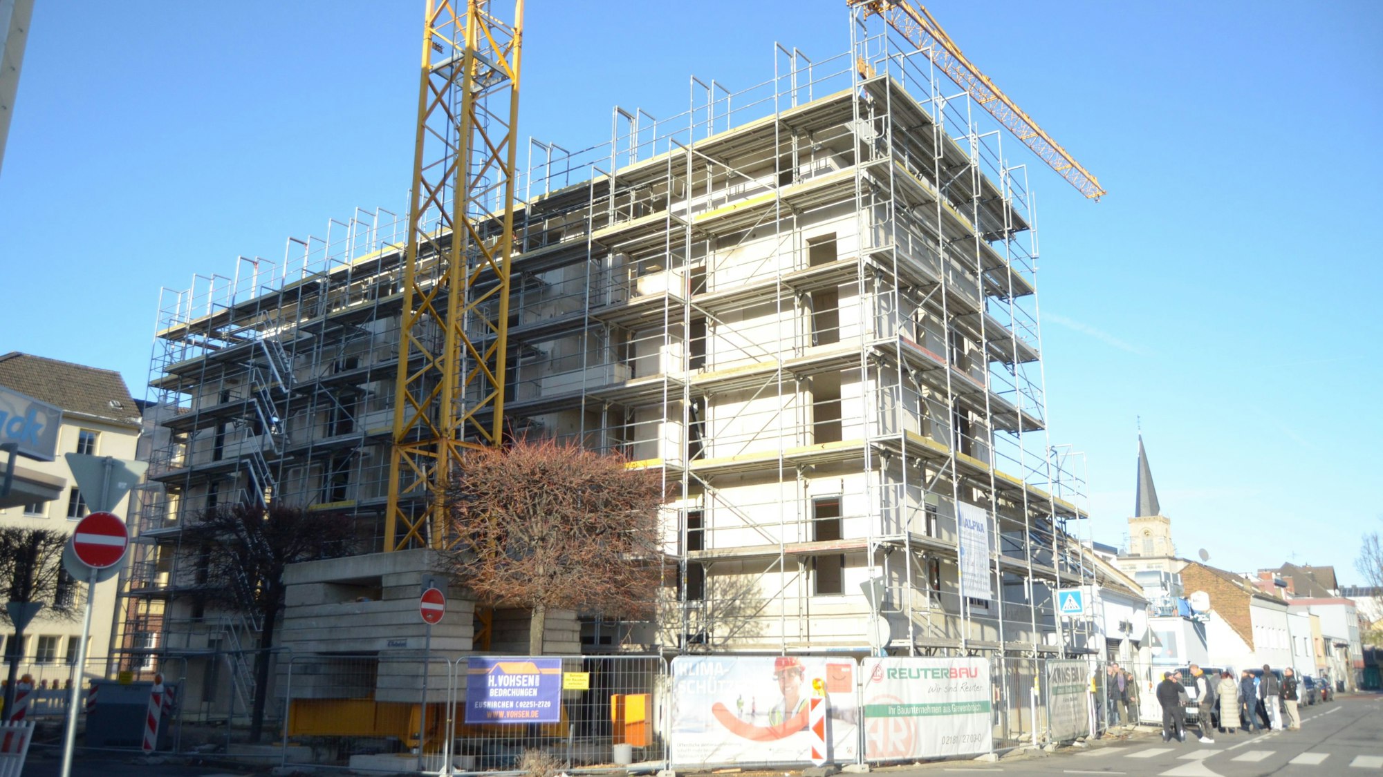 Das neue Wohngebäude in der Euskirchener Innenstadt, im Vordergrund steht ein Baukran, im Hintergrund der Turm der Herz-Jesu-Kirche.
