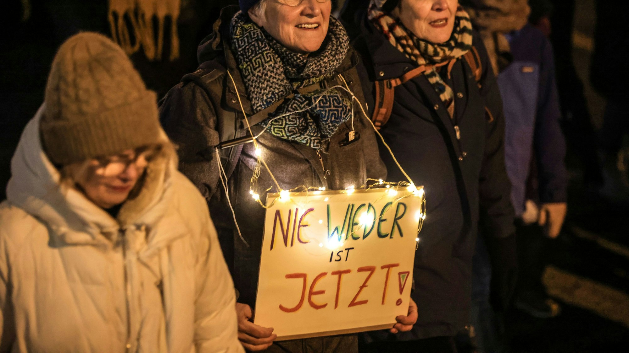 Eine Frau trägt ein Schild mit der Aufschrift „Nie wieder ist jetzt“.