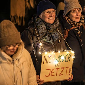 Eine Frau trägt ein Schild mit der Aufschrift ·„Nie wieder ist jetzt“ auf der Demo des Bündnisses gegen „Rassismus in Köln“.