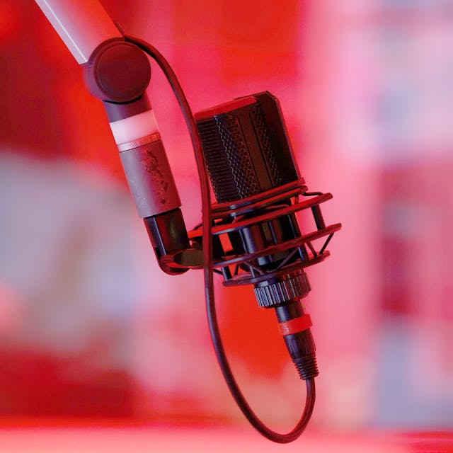 Ein Mikrofon in einem rot beleuchteten Tonstudio