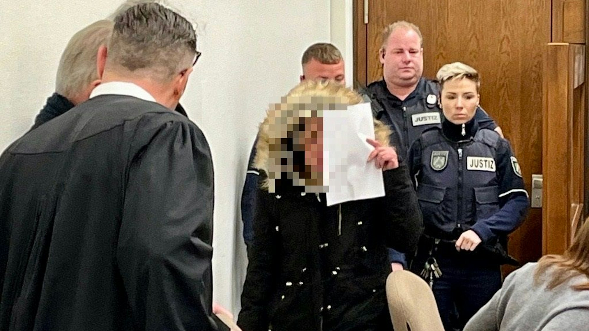 Eine Frau kommt vermummt zu einer Verhandlung im Kölner Landgericht.