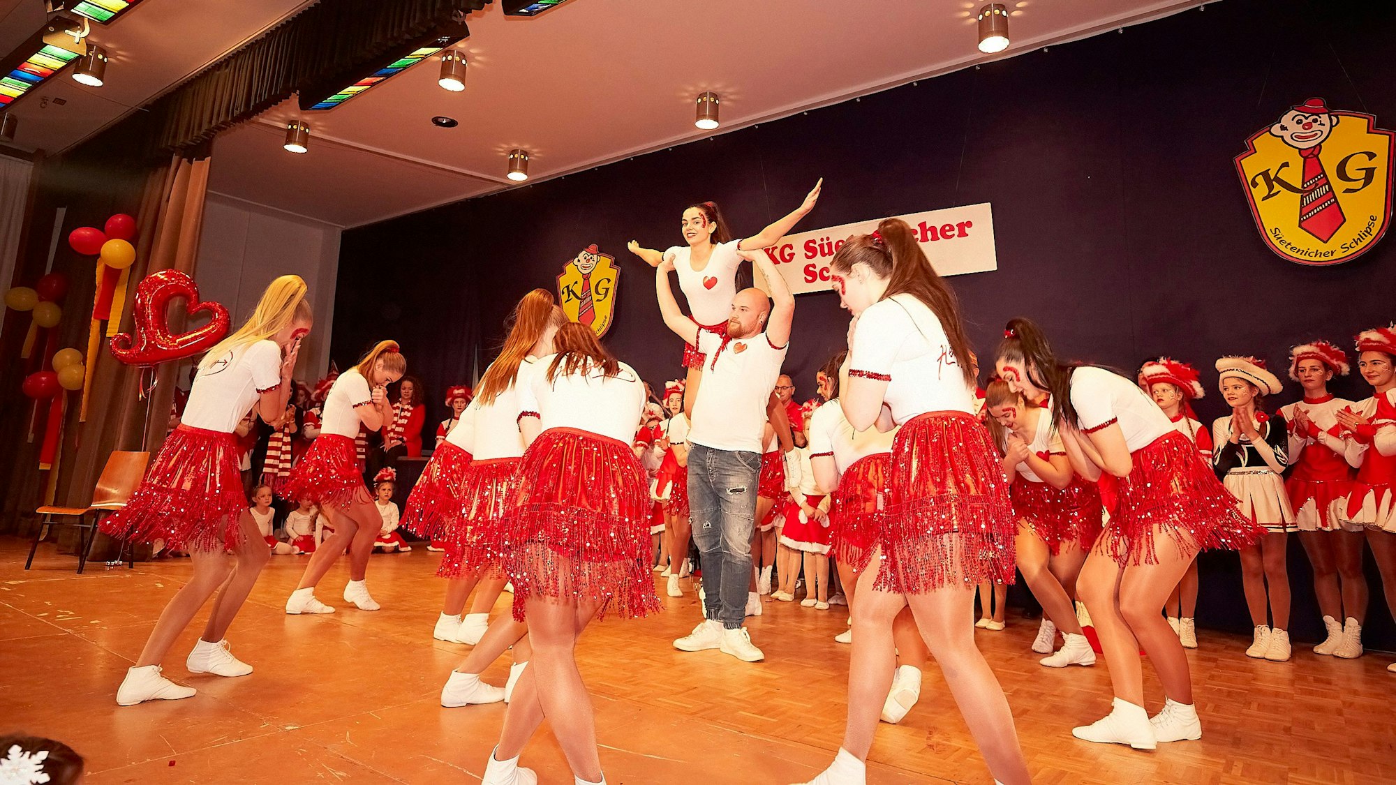 Frauen der Showtanzgruppe IG Ländchen tanzen in roten Röcken und weißen T-Shirts auf der Bühne.