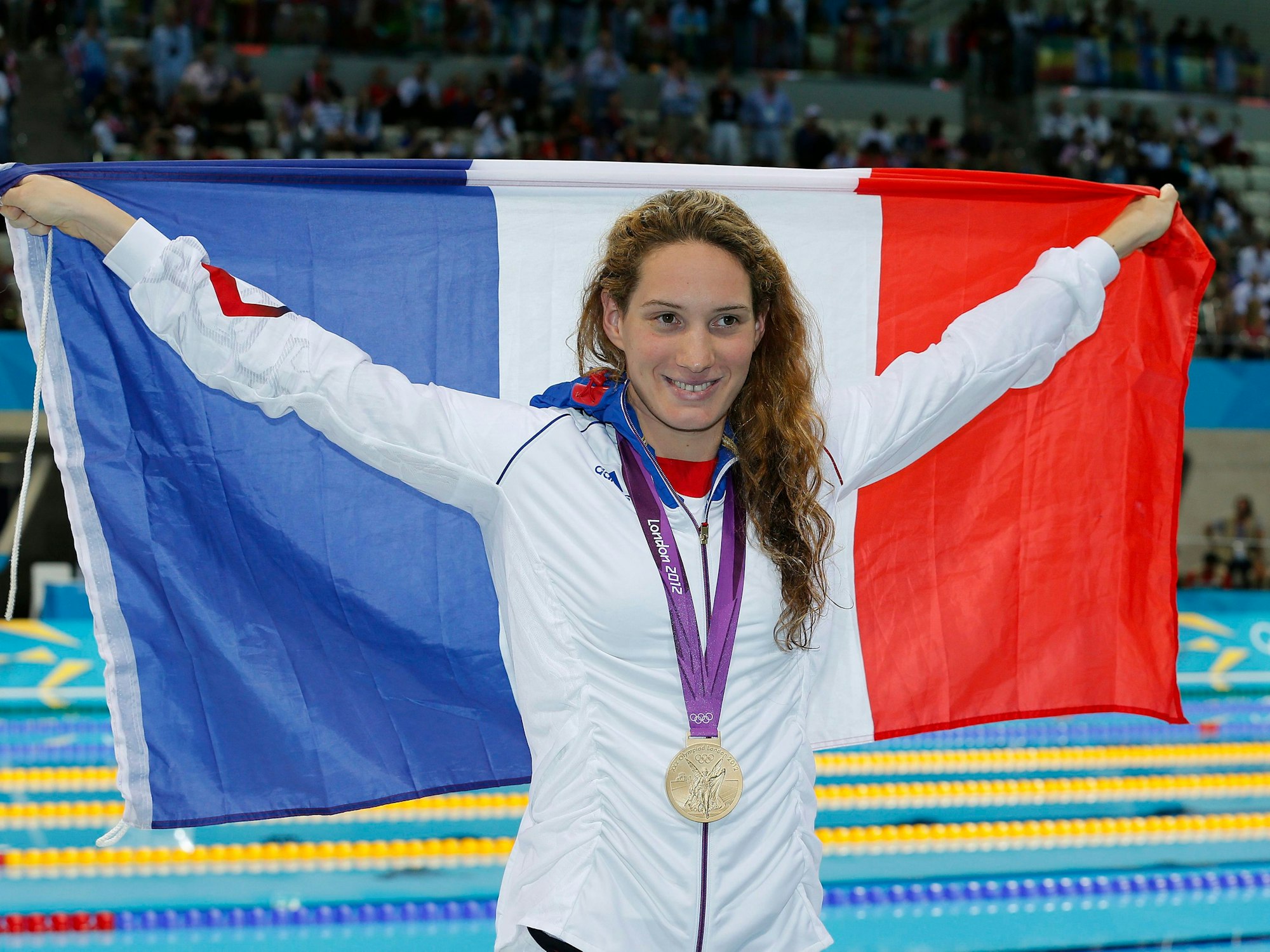 Camille Muffat jubelt mit der französischen Flagge und ihrer Goldmedaille.