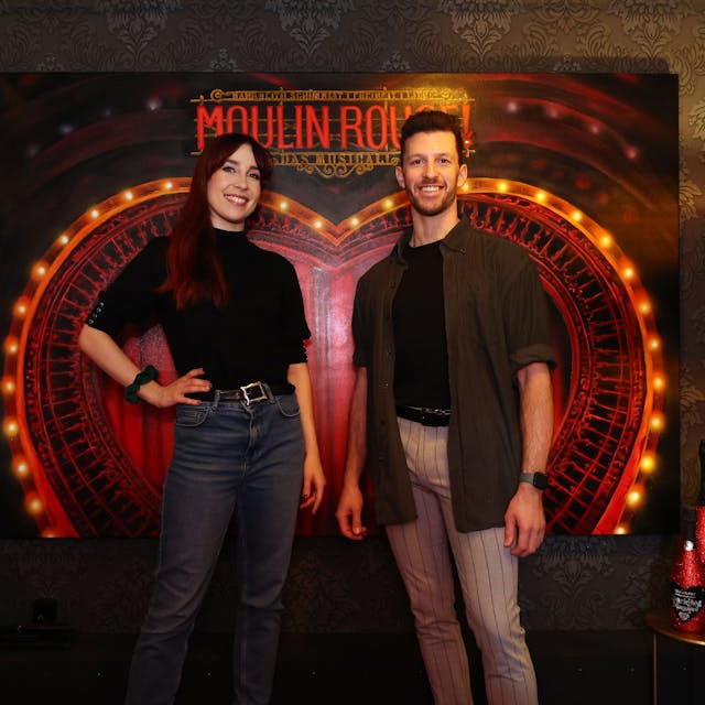 Swing-Darsteller Gabrielle D‘Anthouard und Nathan Saxon im Porträt vor dem Moulin-Rouge-Logo