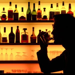 Ein Bar-Besucher sitzt vor einer bunt beleuchteten Bar. (Symbolfoto)