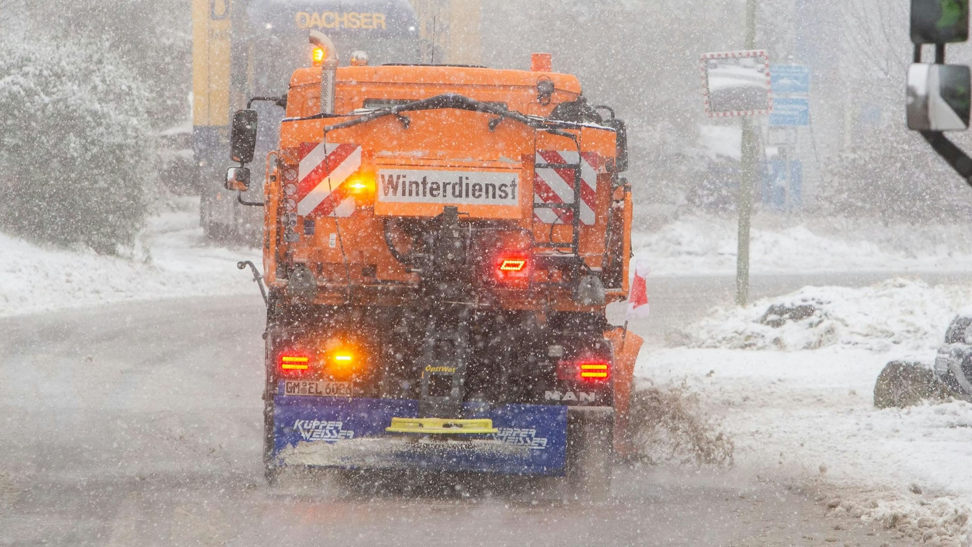 Ein Räumfahrzeug des Winterdienstes befreit eine verschneite Straße von Neuschnee und Schlamm. Währendessen fallen dicke Schneeflocken. (Archivbild)