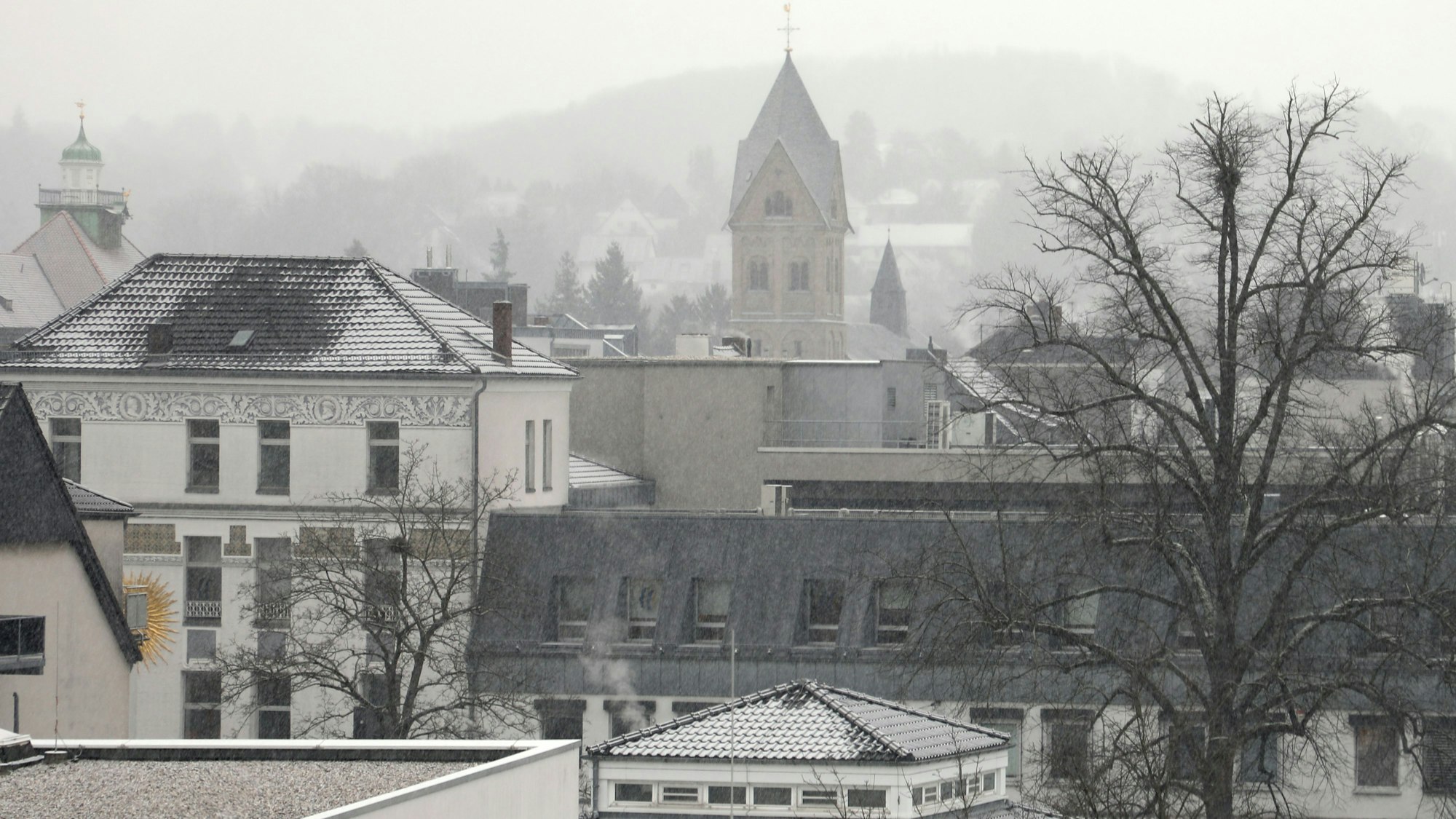 Kirchturm und Rathausturm von Bergisch Gladbach sind durch einen Schneeschleier zu sehen.