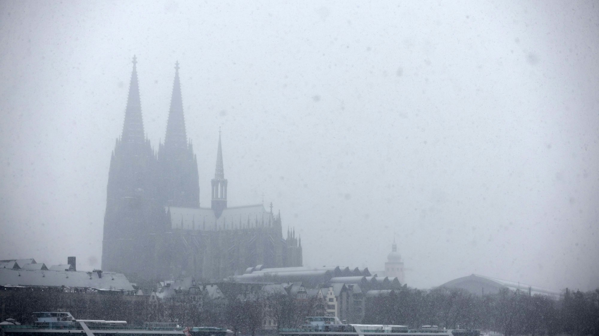 Der Schneeflocken fallen und im Hintergrund ist der Kölner Dom