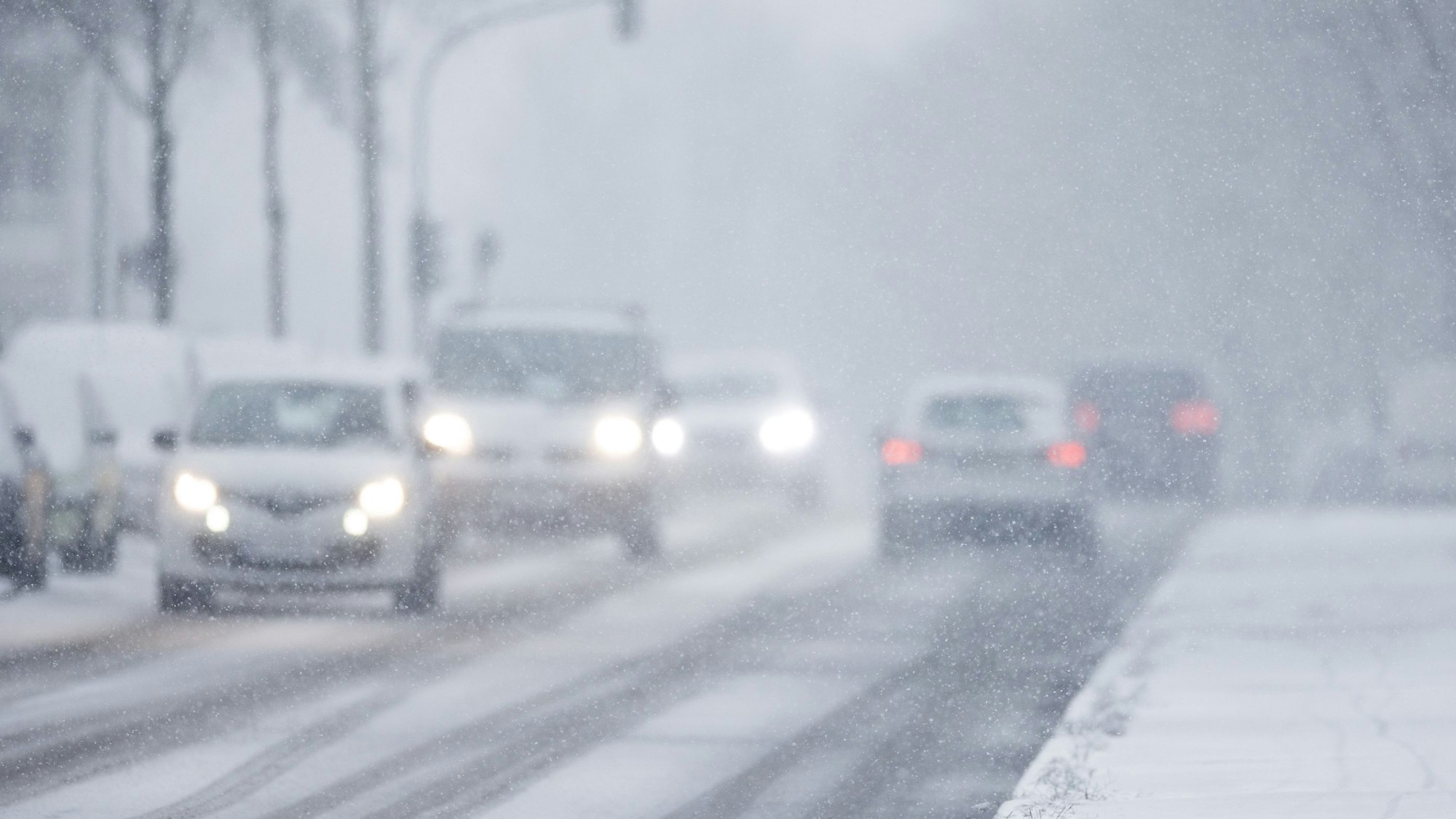 Nur langsam kommen Autos in der Kölner Innenstadt im dichten Schneetreiben voran.