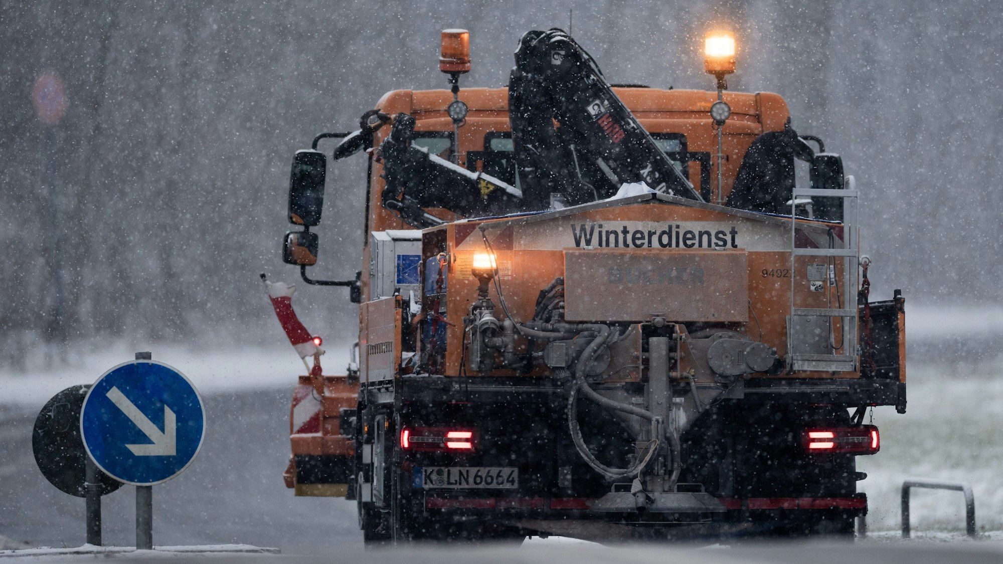 Ein Räum- und Streufahrzeug des Winterdienstes fährt im dichten Schneetreiben auf der Gleueler Straße am Decksteiner Weiher.