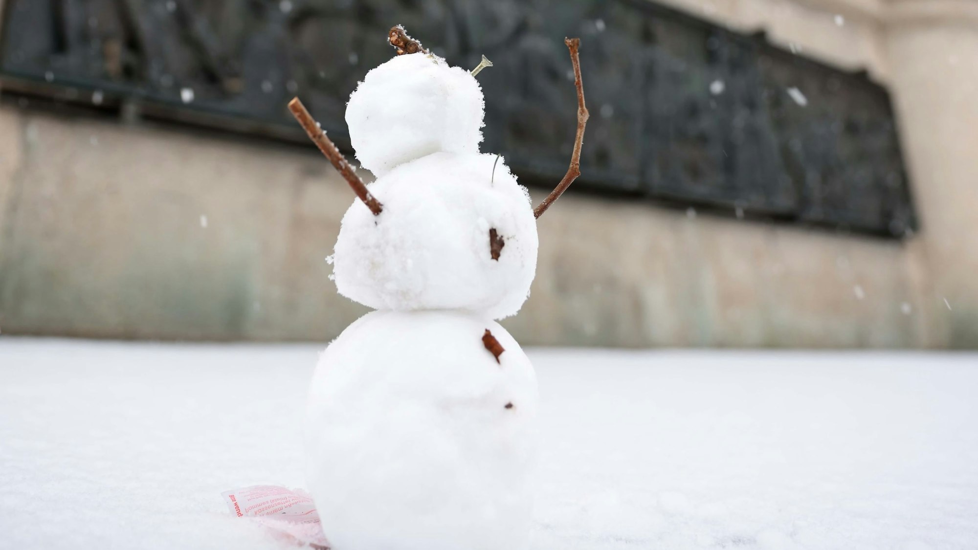 Ein kleiner Schneemann steht auf der Straße.