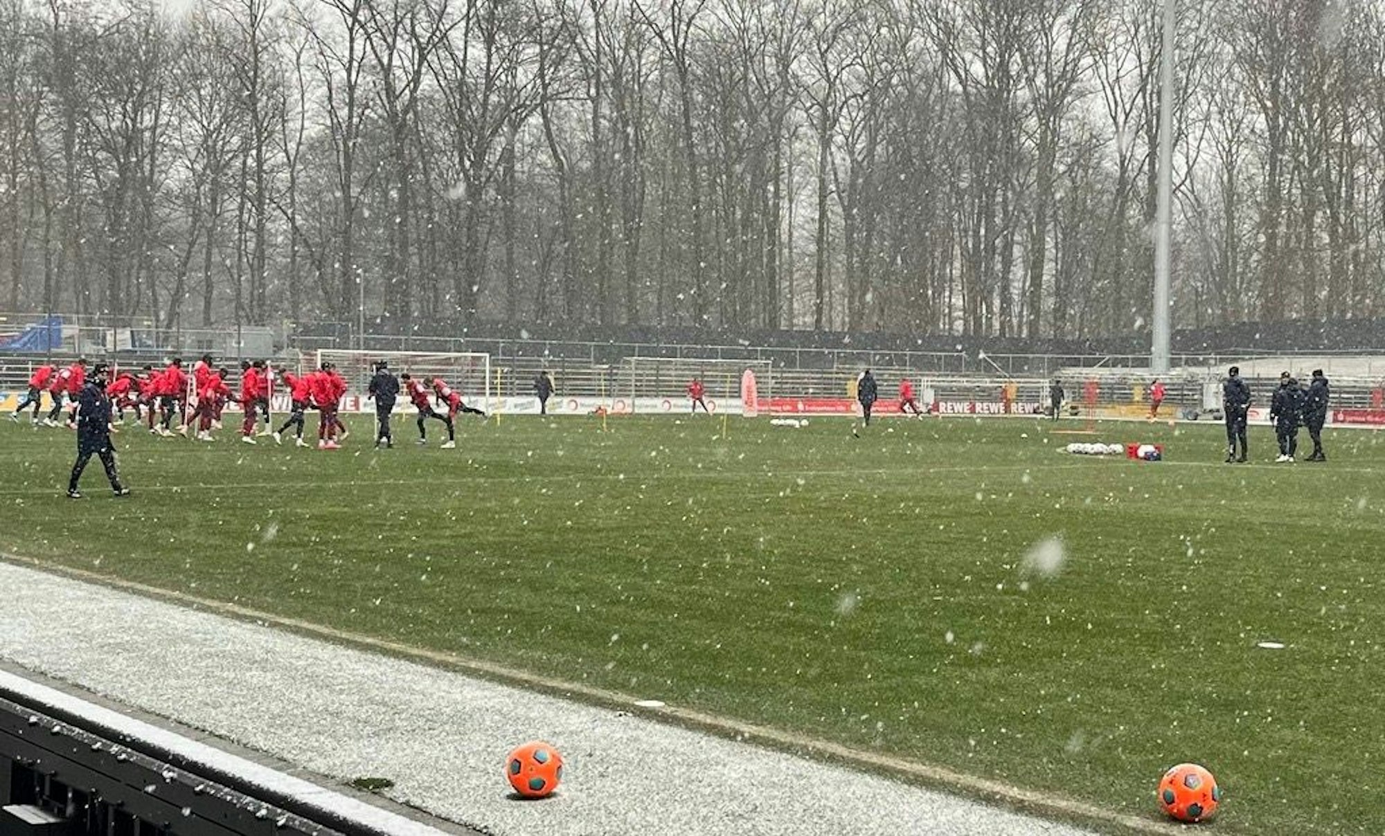 Die FC-Profis wärmen sich bei Schneefall auf.