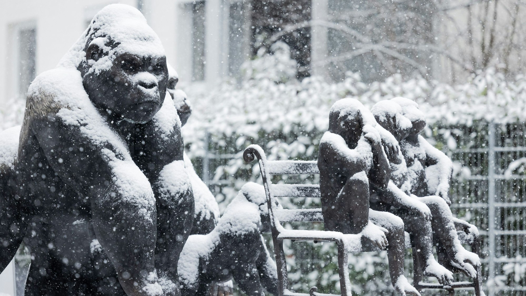Gorilla-Figuren stehen am Straßenrand im dichten Schneetreiben.