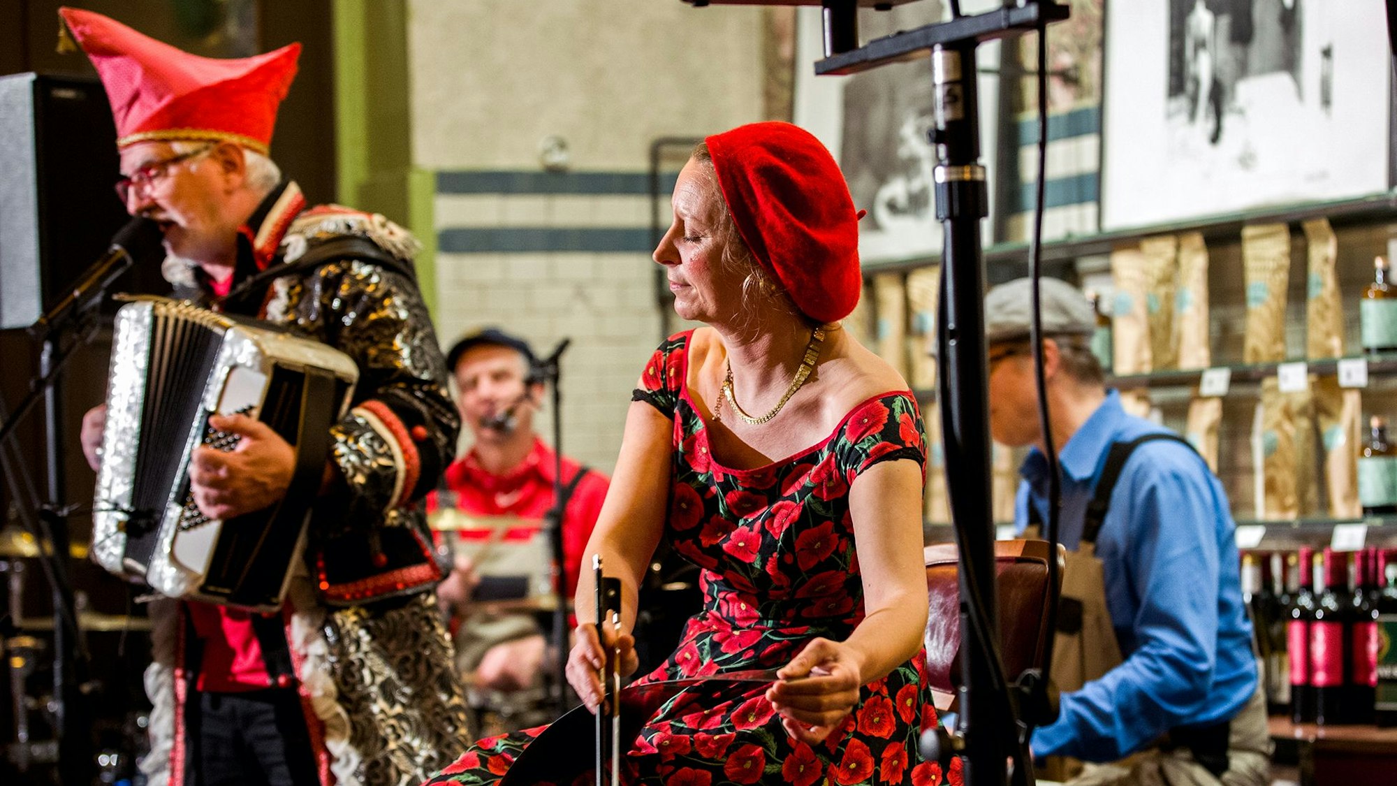 Mann im Karnevalskostüm, der Akkodeon spielt und Frau, die einem Instrument spielt.
