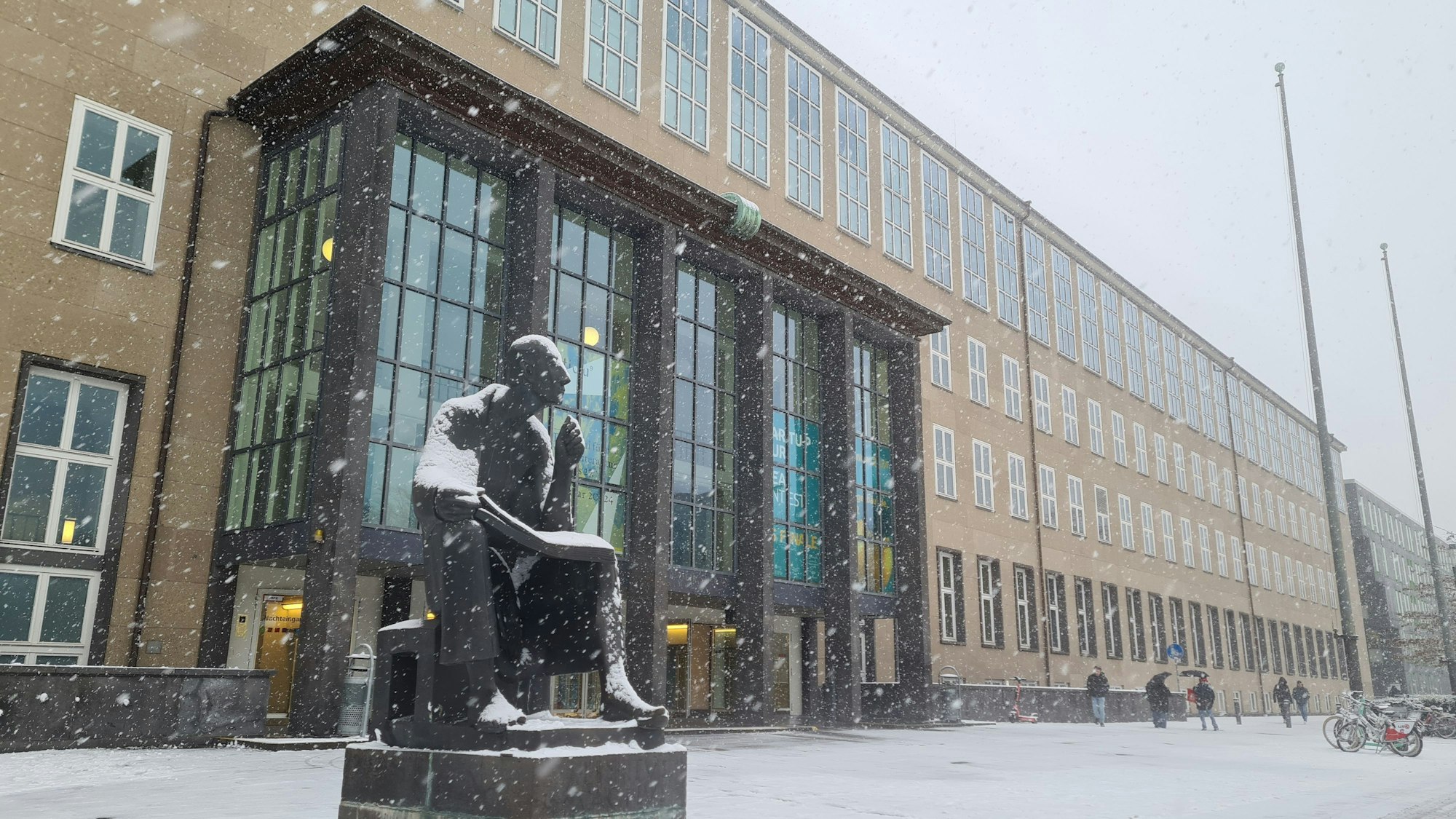Schnee an einem Platz mit einer Statue und einem Gebäude