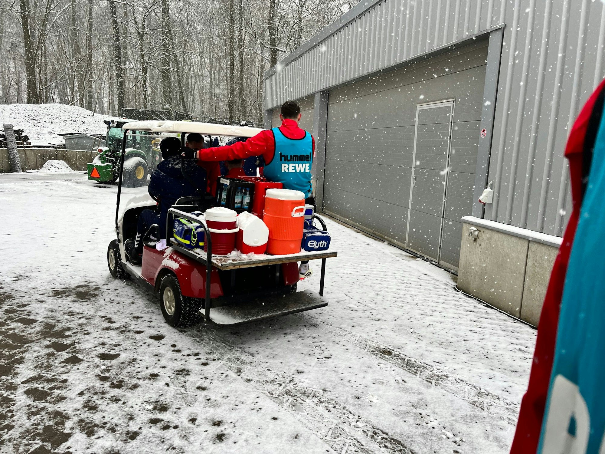 Ein Golfwagen mit Ausrüstung und einigen Teammitgliedern fährt vom Franz-Kremer-Stadion Richtung Geißbockheim.