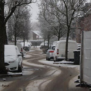 Eine verschneite Straße mit deutlichen Reifenspuren.