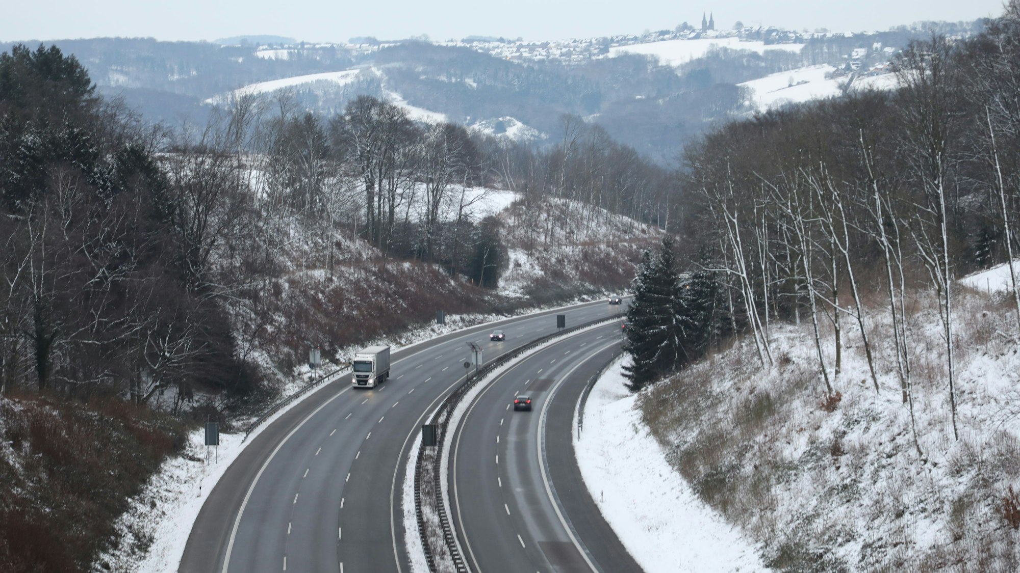 Eine relativ freie Autobahn 4 gibt den Blick frei auf eine verschneite Winterlandschaft mit dem Ort Marialinden am Horizont.