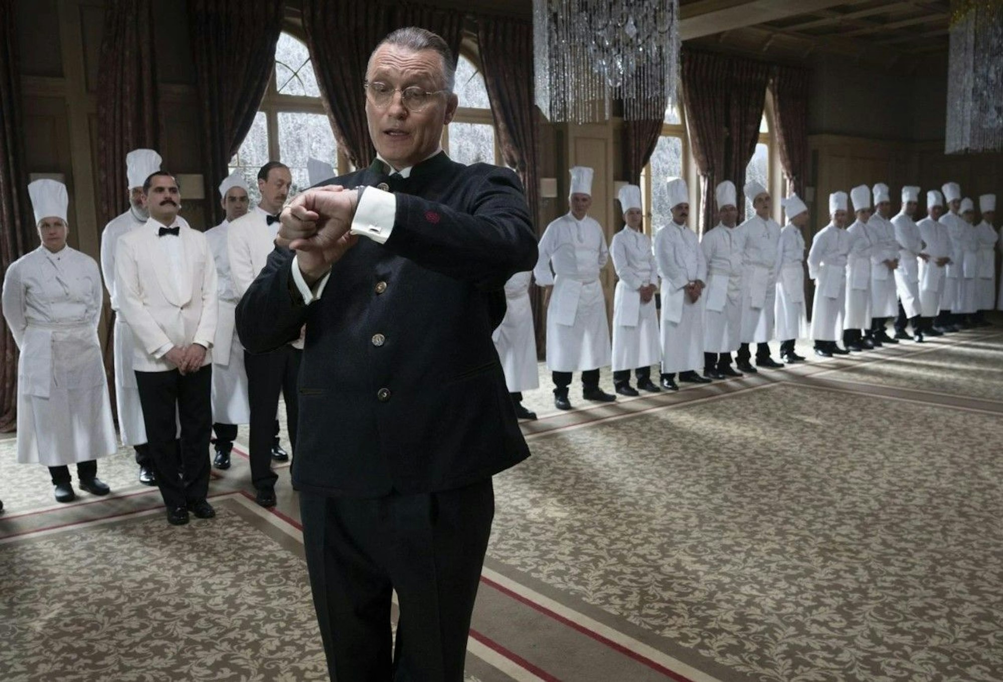 Der Schauspieler Oliver Masucci dreht eine Szene beim Film „The Palace“. Im Hintergrund stehen ganz viele Köche.
