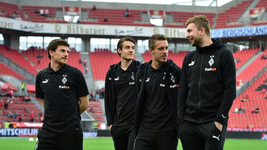 Spieler von Borussia Mönchengladbach begehen den Platz und führen Unterhaltung.