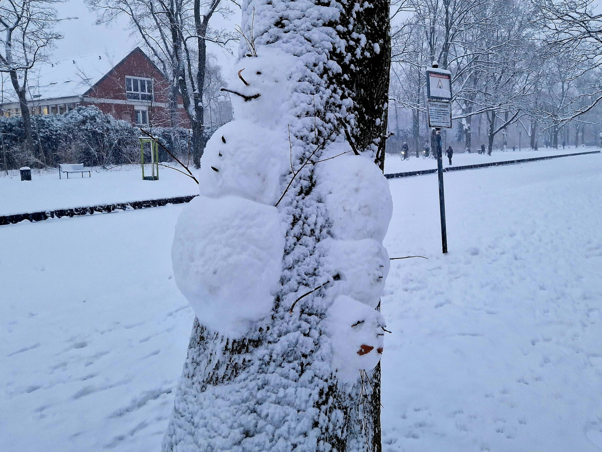 Zwei Schneemänner an einem Baum.