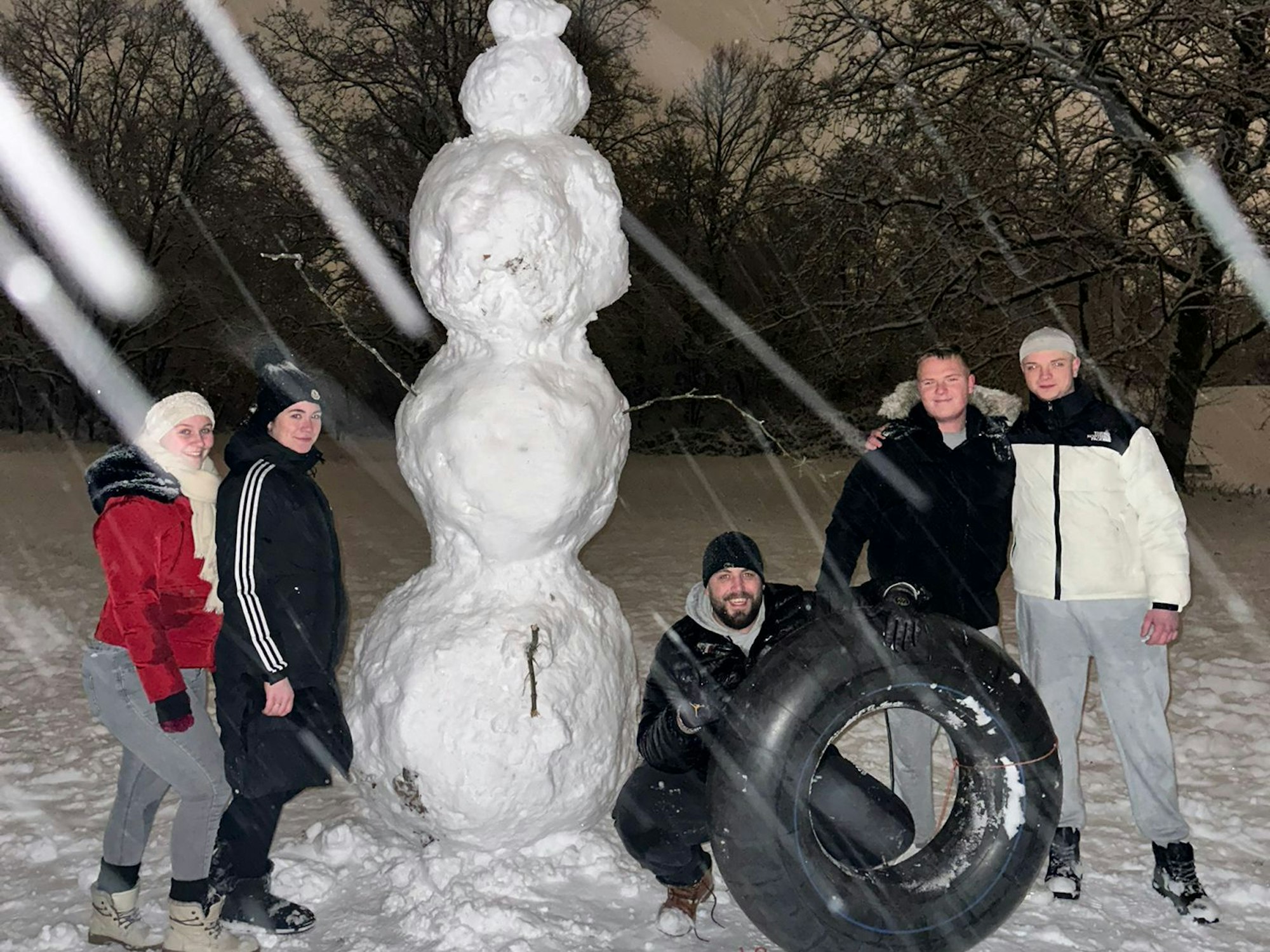 Eine Gruppe steht neben einem Schneemann.