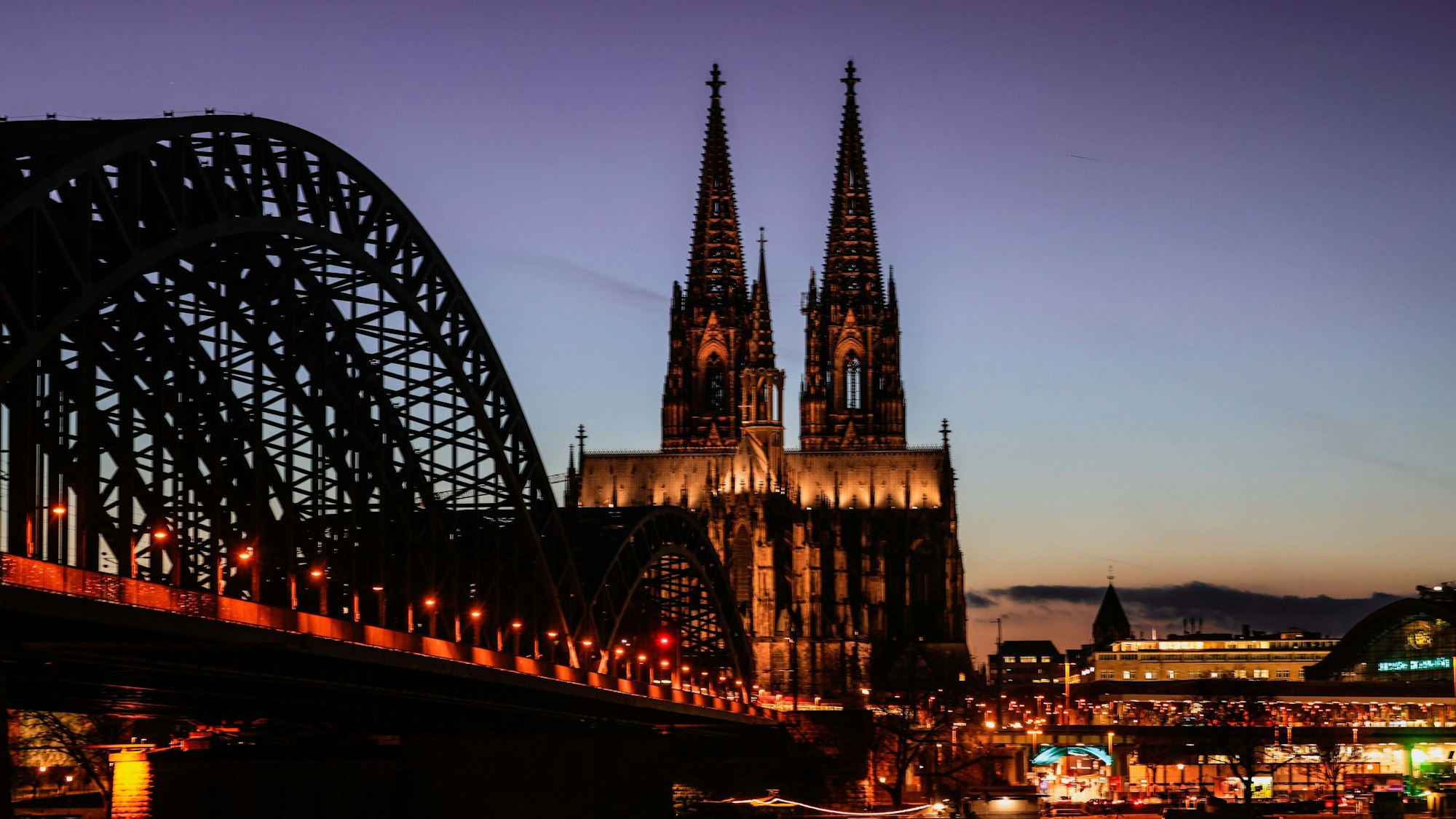 Der Dom und die Hohenzollernbrücke sind am Abend beleuchtet.
