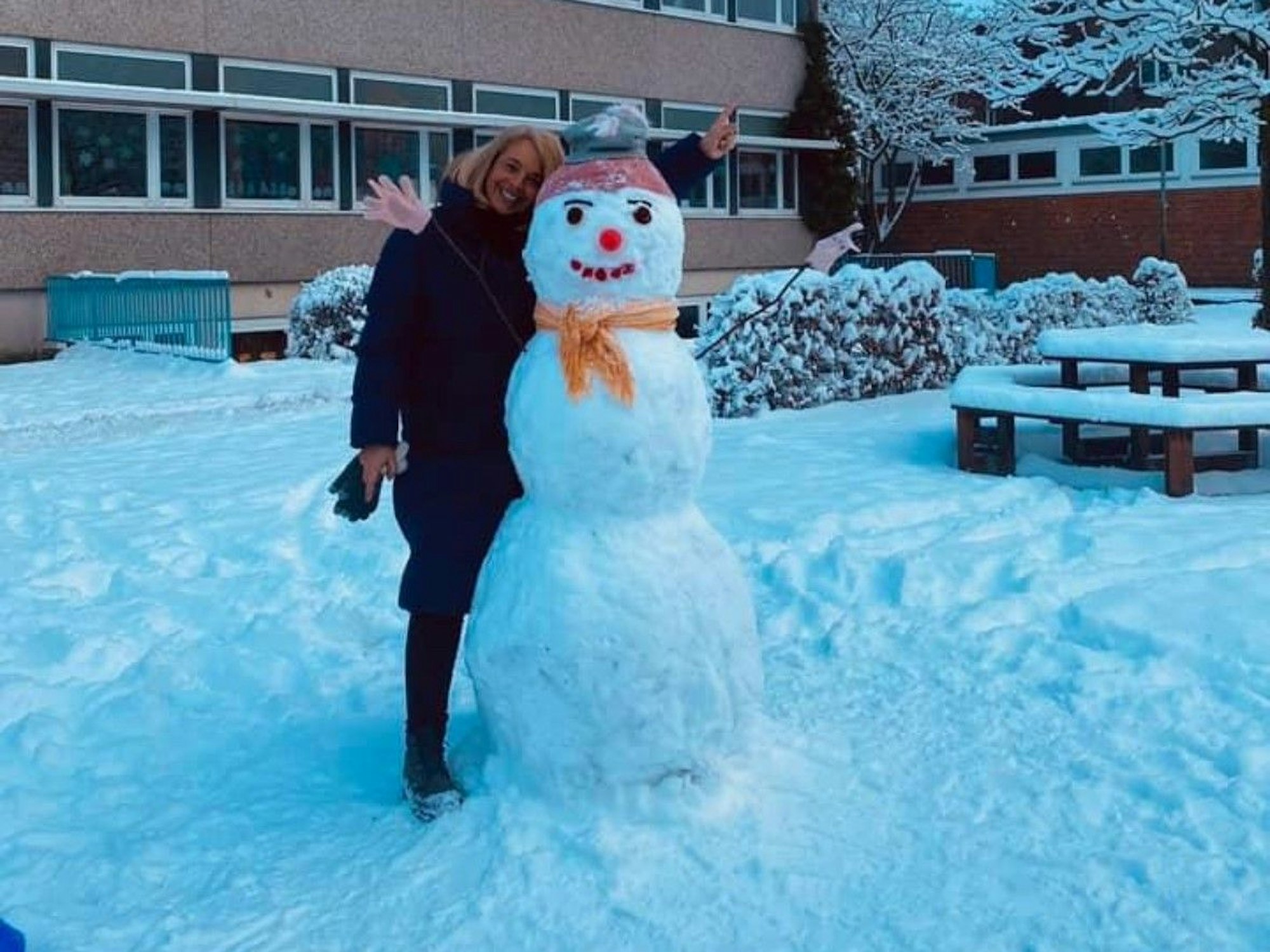 Eine Frau steht neben einem Schneemann.