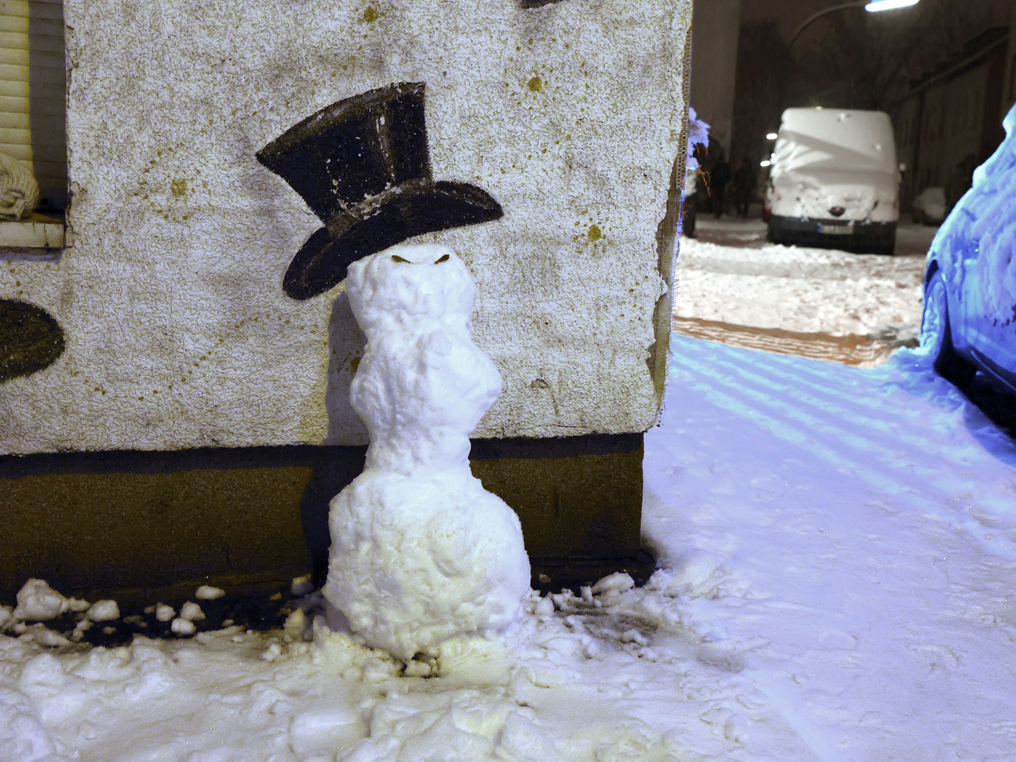 Ein Schneemann vor einem angemalten Hut an einer Hauswand auf der Marienstr.