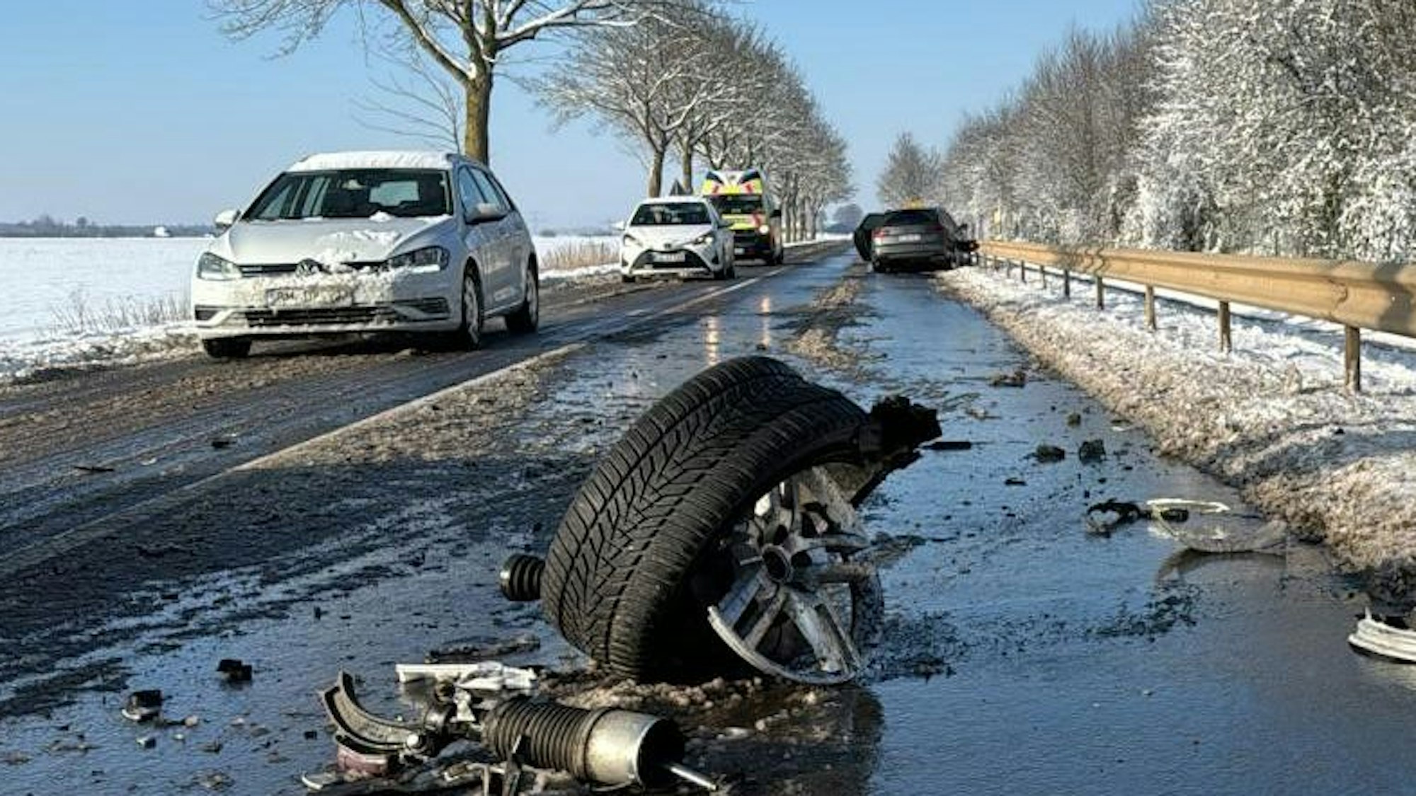 Das Bild zeigt eine verschneite Straße und ein abgerissenes Wagenrad eines Autos auf der Fahrbahn.