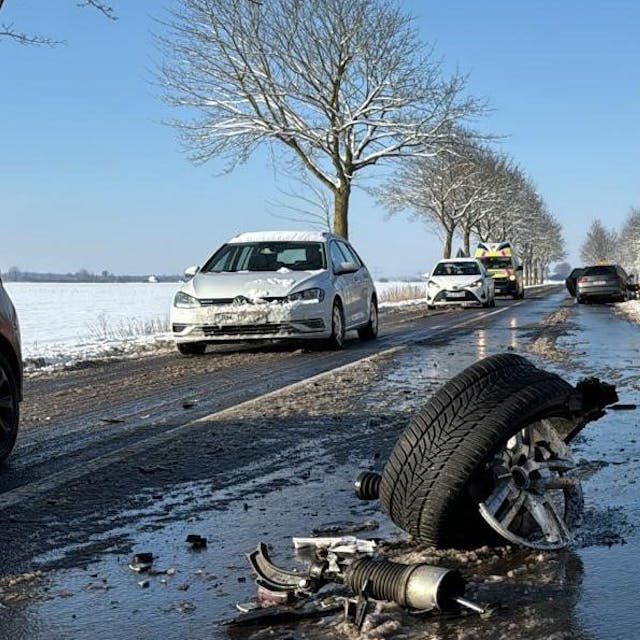 Das Bild zeigt eine verschneite Straße und ein abgerissenes Wagenrad eines Autos auf der Fahrbahn.