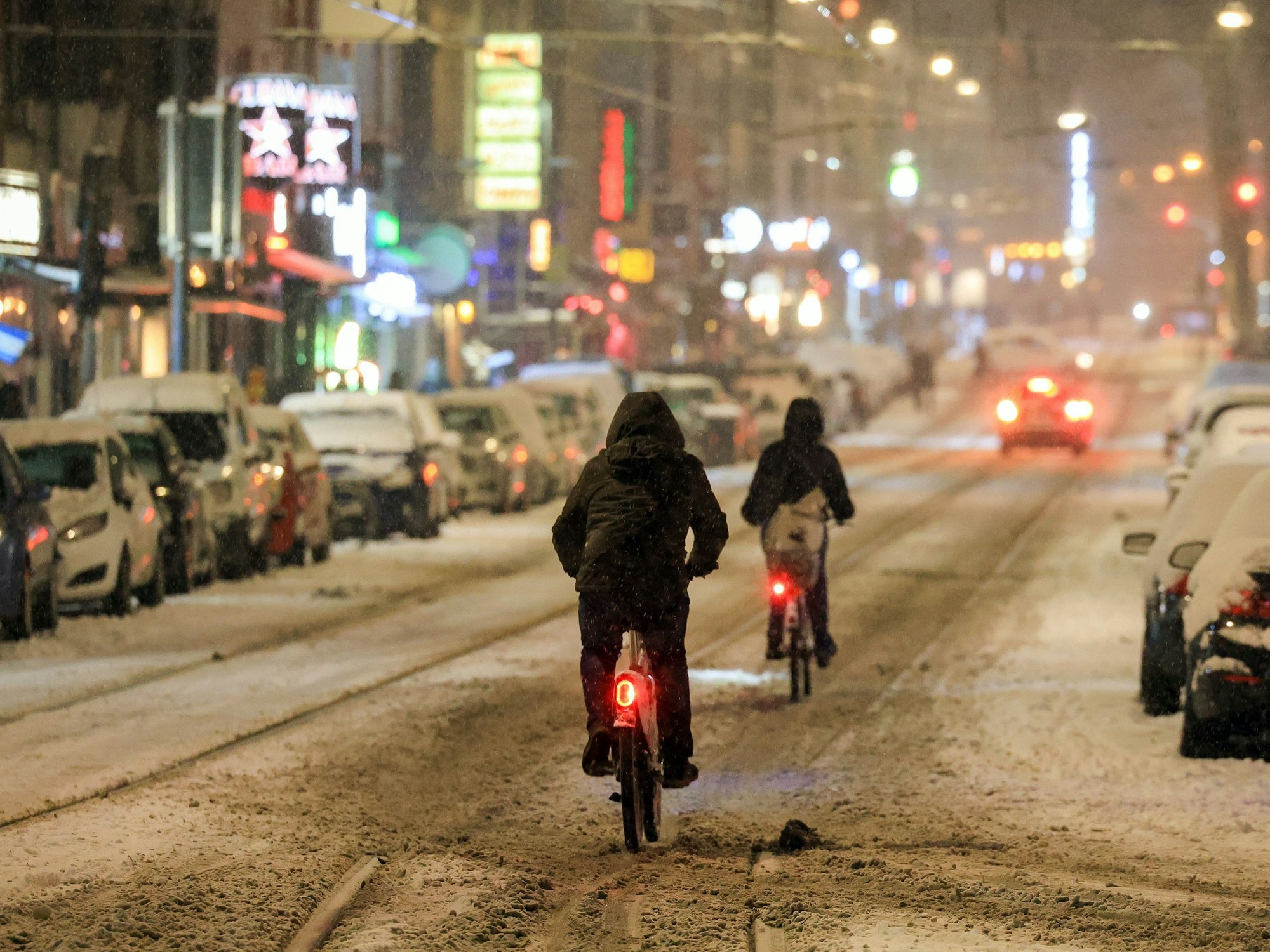 Fahrradfahrer fahren im Schnee über die Zülpicher Straße.