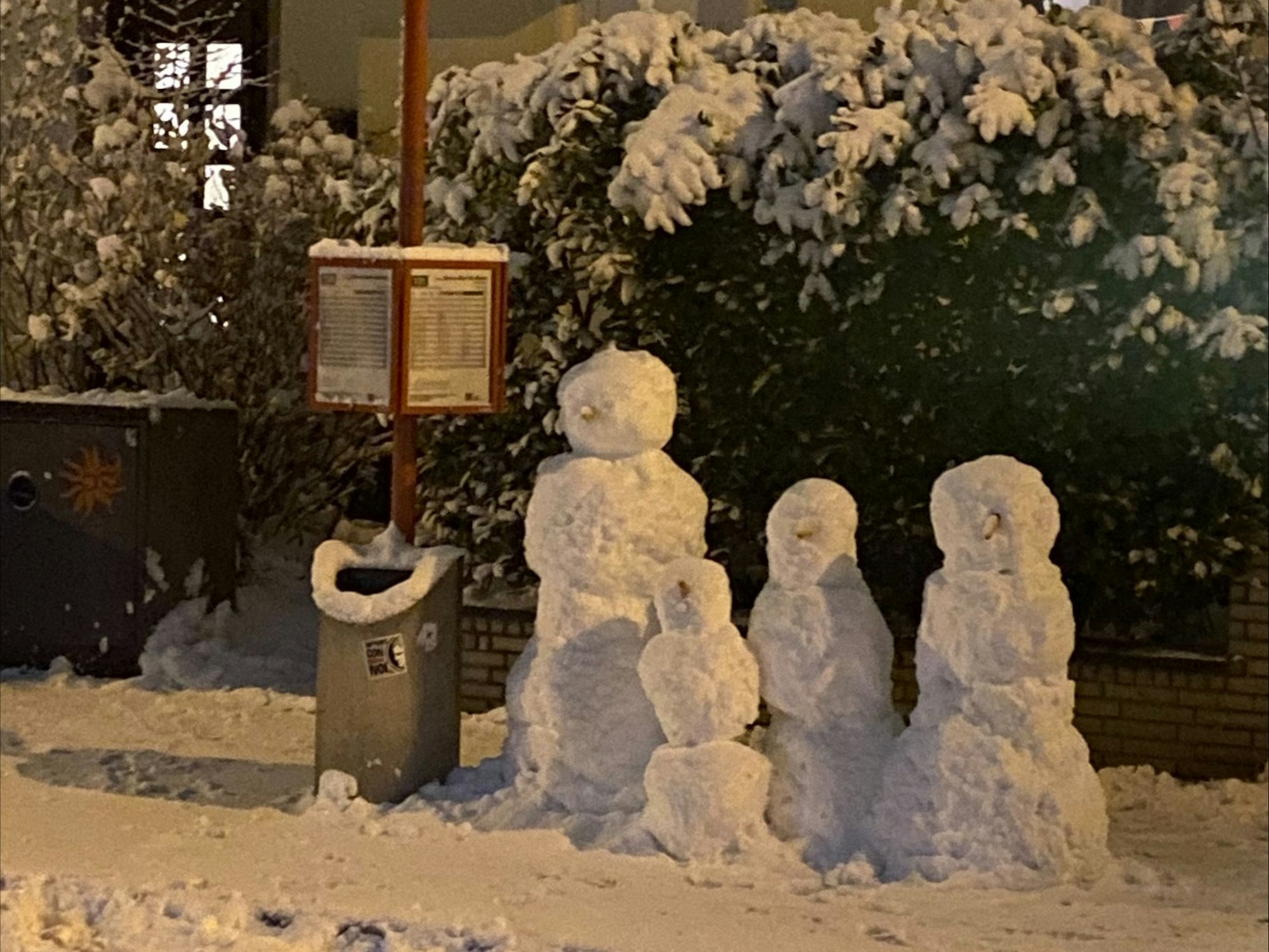 Schneemänner an einer Bushaltestelle.