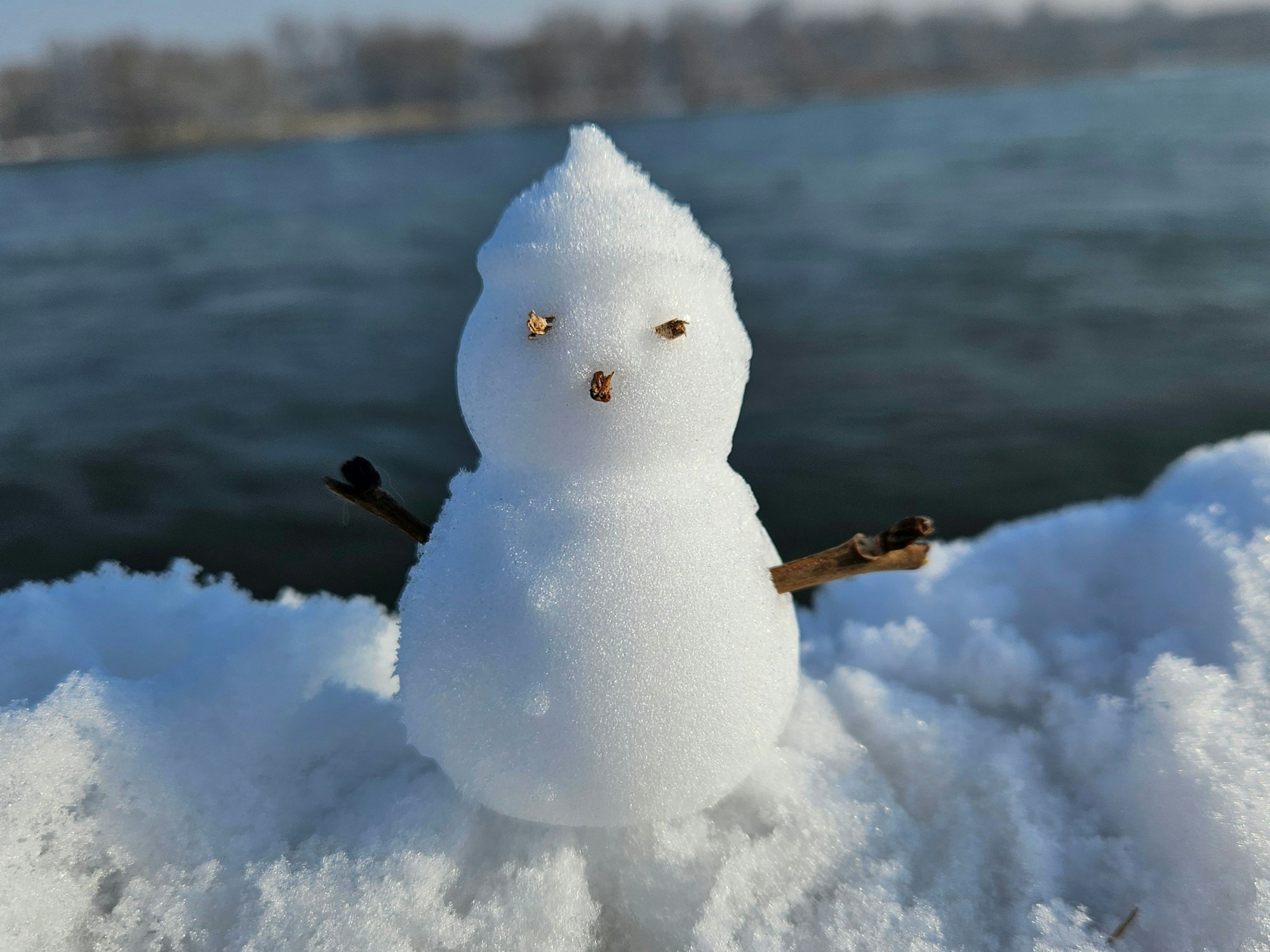 Ein kleiner Schneemann auf einem Geländer.