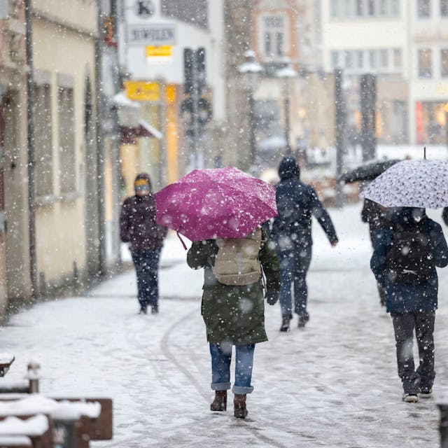 Menschen gehen bei dichtem Schneefall durch die Bonner Innenstadt.