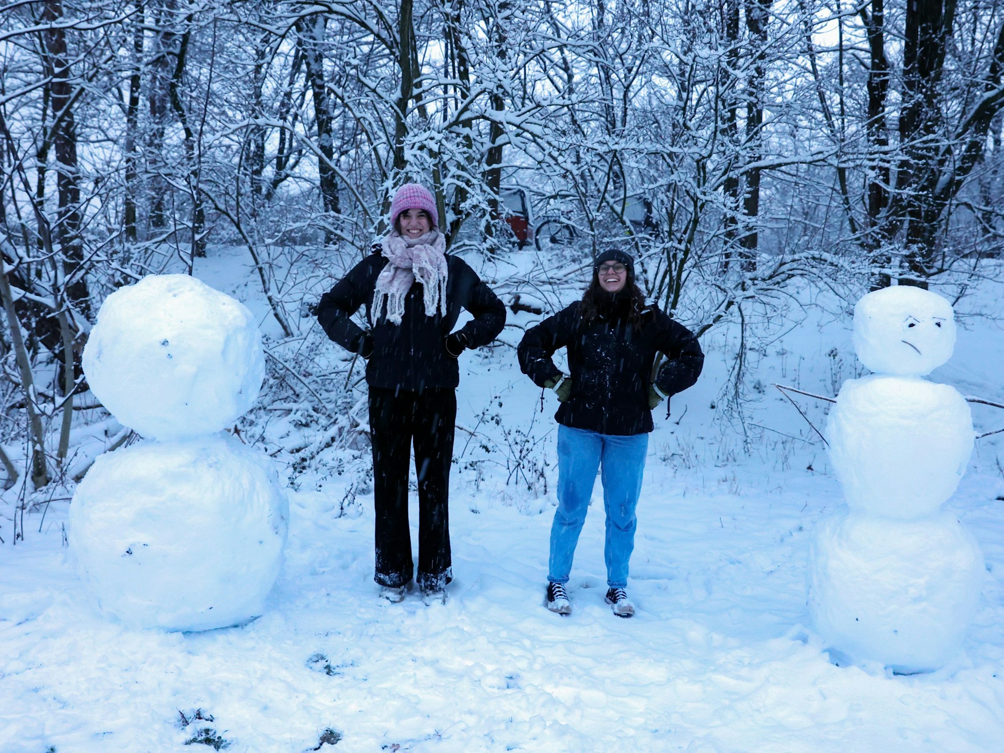 Die Kölnerinnen Emma und Marie stehen zwischen ihren gebauten Schneemännern.