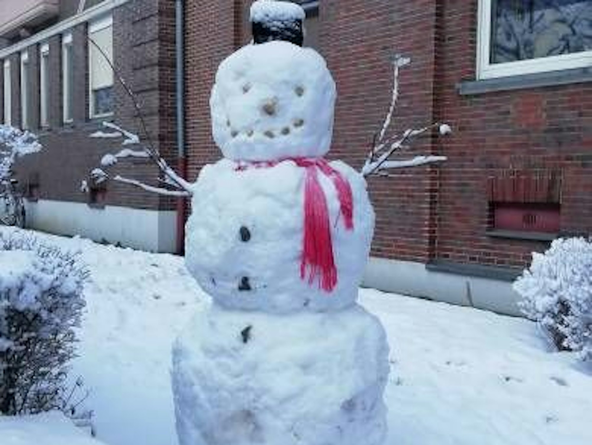 Ein Schneemann steht vor einem Haus.