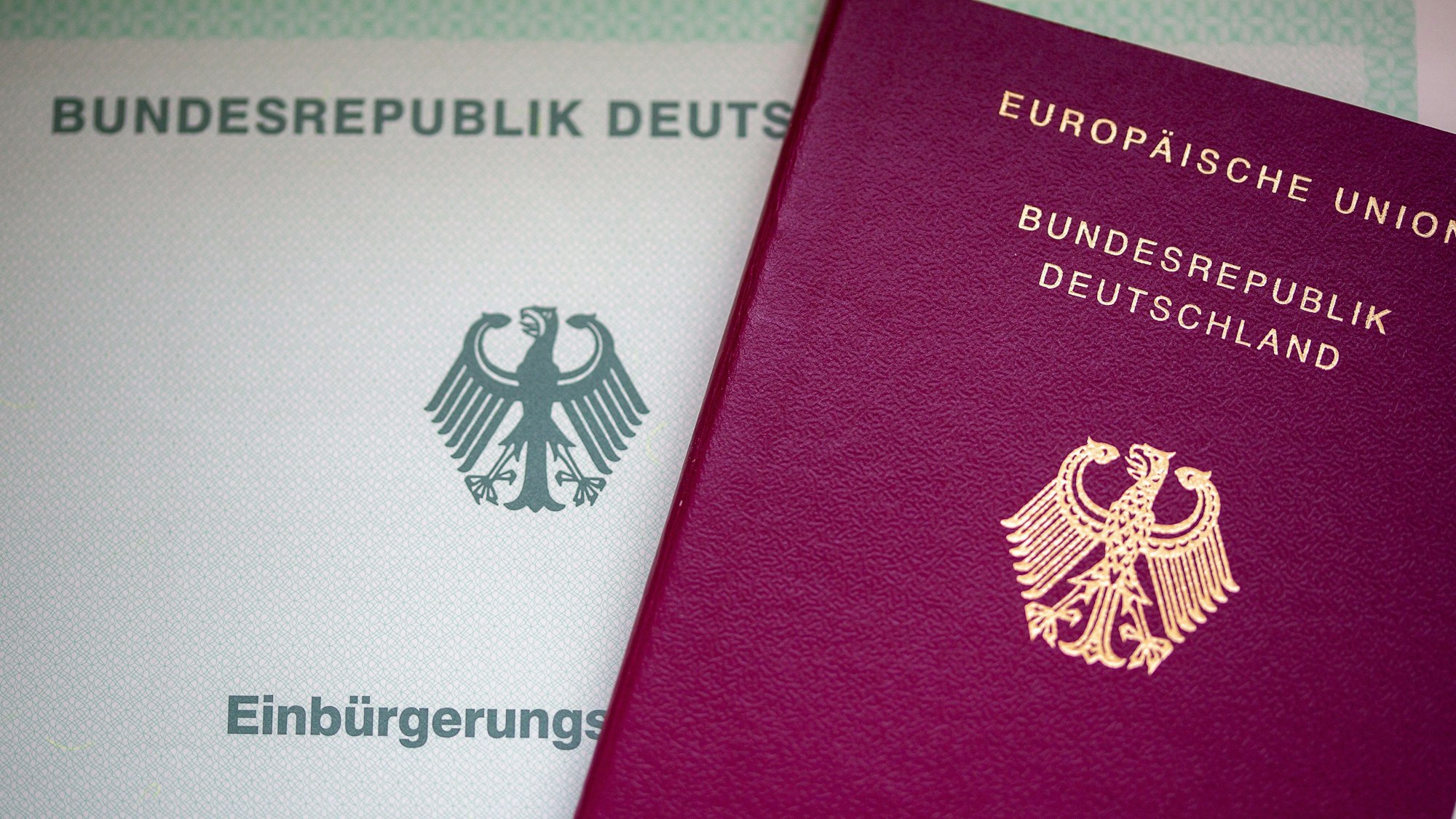 Eine Einbürgerungsurkunde der Bundesrepublik Deutschland (l) und ein deutscher Reisepass liegen auf einem Tisch. Ein neues Gesetz erleichtert es, die deutsche Staatsbürgerschaft zu bekommen.