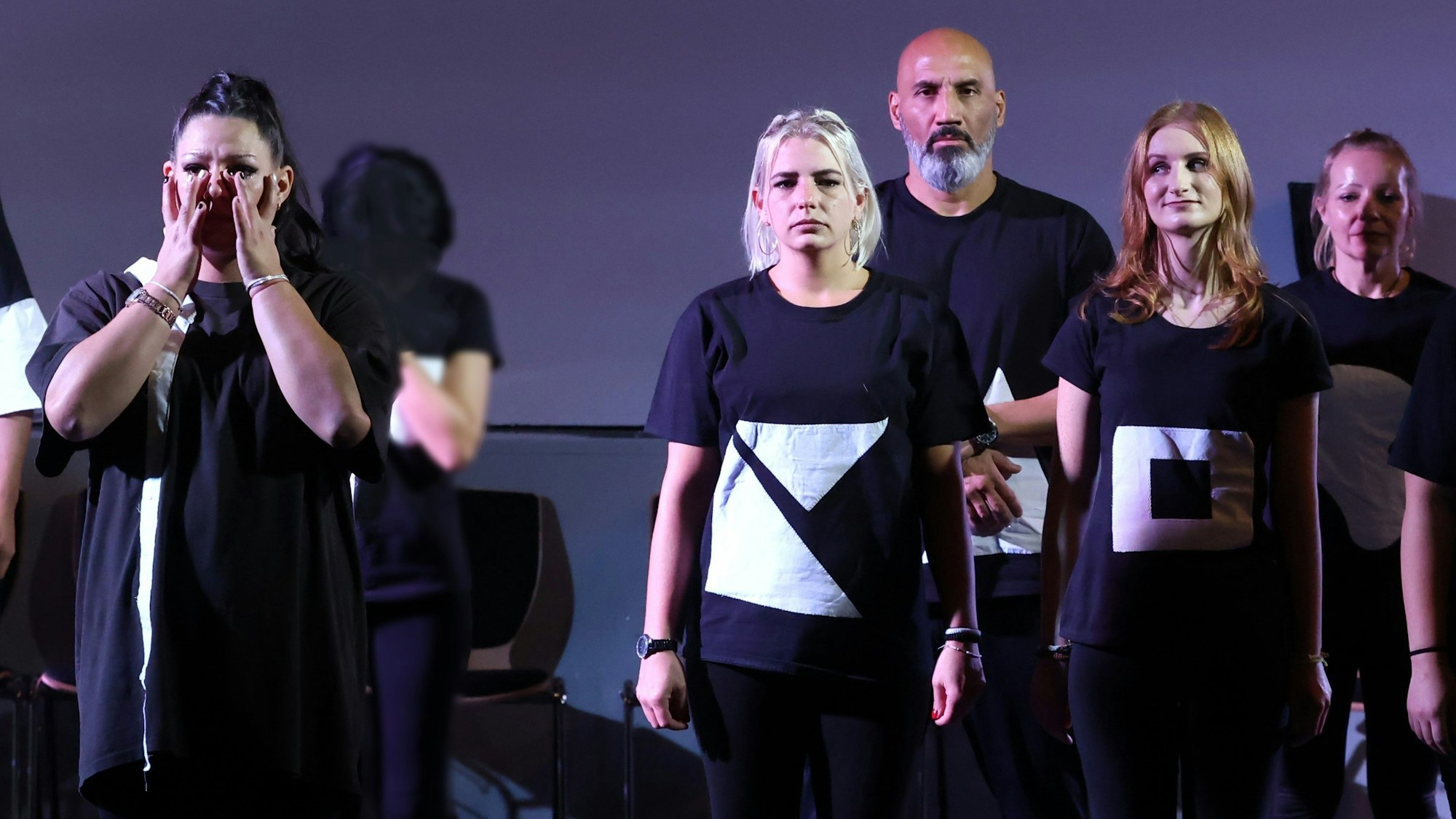 Fünf Inhaftierte in schwarz-weißen Kostümen stehen auf der Bühne der JVA Ossendorf, eine von ihnen muss weinen.