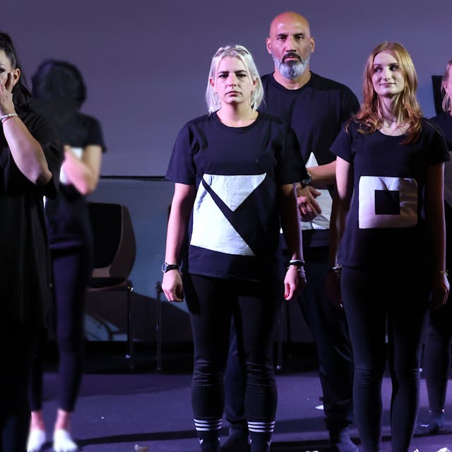 Fünf Inhaftierte in schwarz-weißen Kostümen stehen auf der Bühne der JVA Ossendorf, eine von ihnen muss weinen.