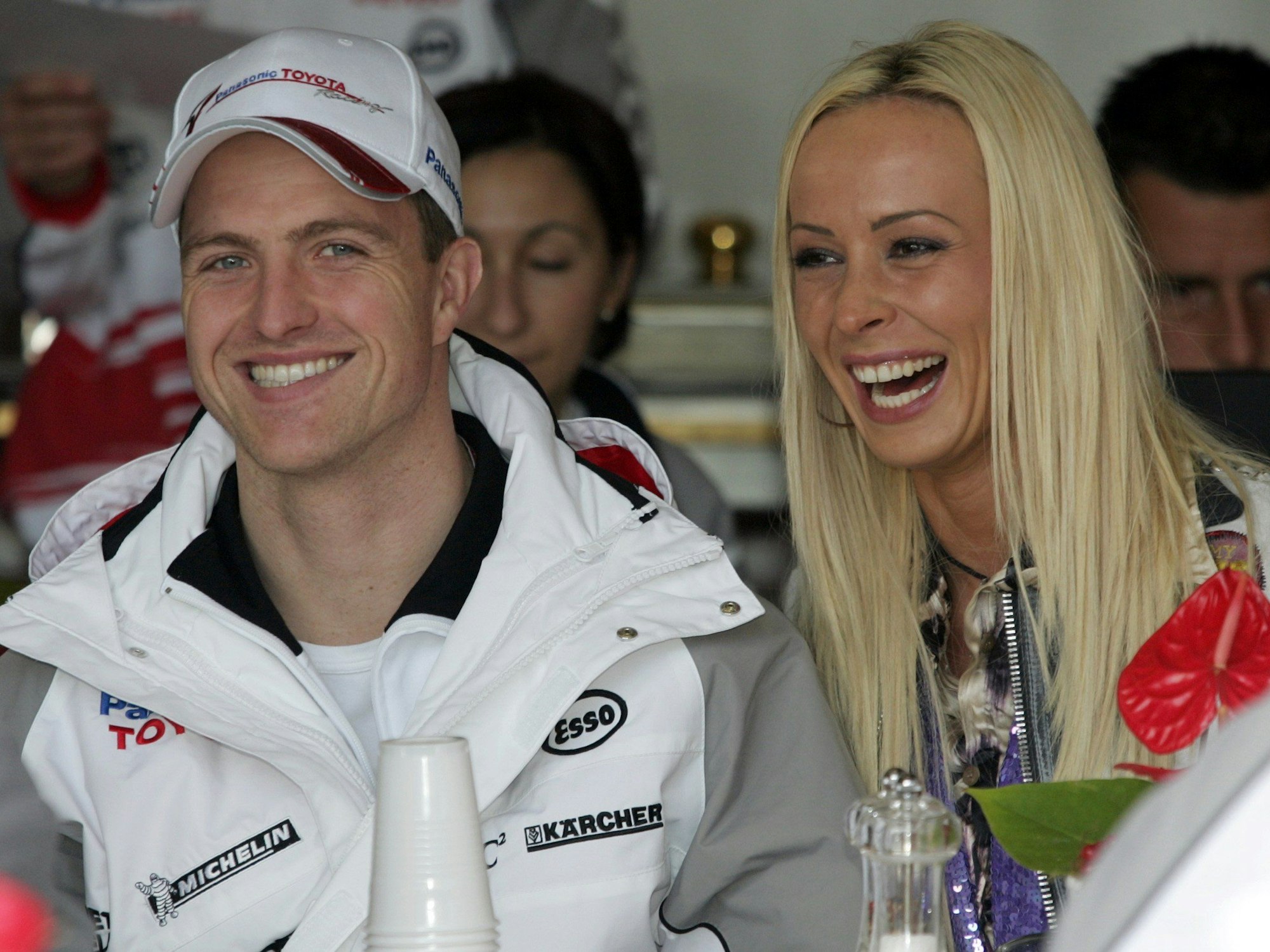 Der deutsche Formel-1-Pilot Ralf Schumacher (links) und seine Frau Cora Schumacher (rechts) lachen auf der Grand-Prix-Strecke im Albert Park, hier im März 2005 in Melbourne, Australien.