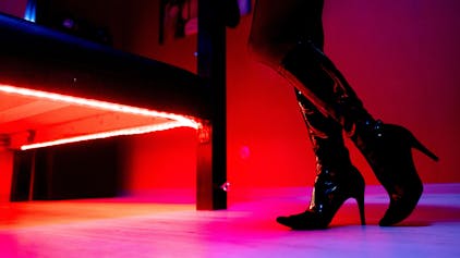 Eine Prostituierte steht vor der roten Beleuchtung unter einem Bett in einem Studio.&nbsp;
