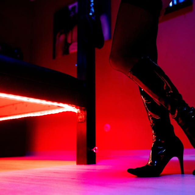 Eine Prostituierte steht vor der roten Beleuchtung unter einem Bett in einem Studio.&nbsp;